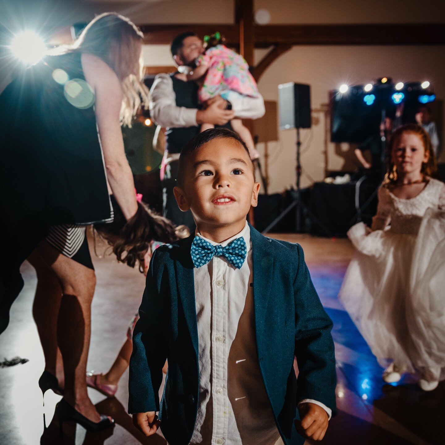 There's nothing more adorable than kiddos on a reception dance floor! 💖
.
.
.
.
.
[Image Description: A young boy with darker skin and dark brown hair is wearing a blue suit and blue polka-dot bow tie. He is on a dance floor and there are people dan