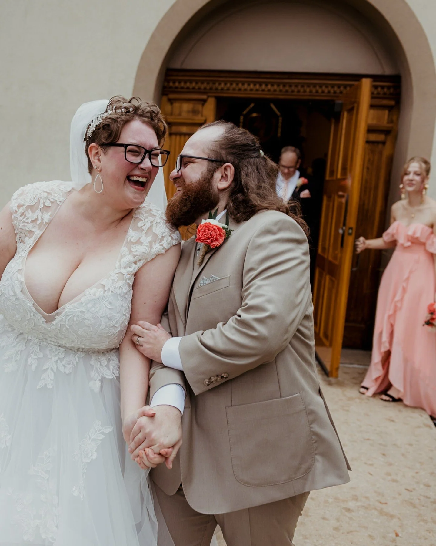 Happy anniversary to Helen + Joseph! 🎉💖
.
.
.
.
.
[Image Description: A white non-binary person with short reddish brown hair and dark glasses is wearing a white wedding dress with lace cap sleeves and laughing with a white man with long dark brown