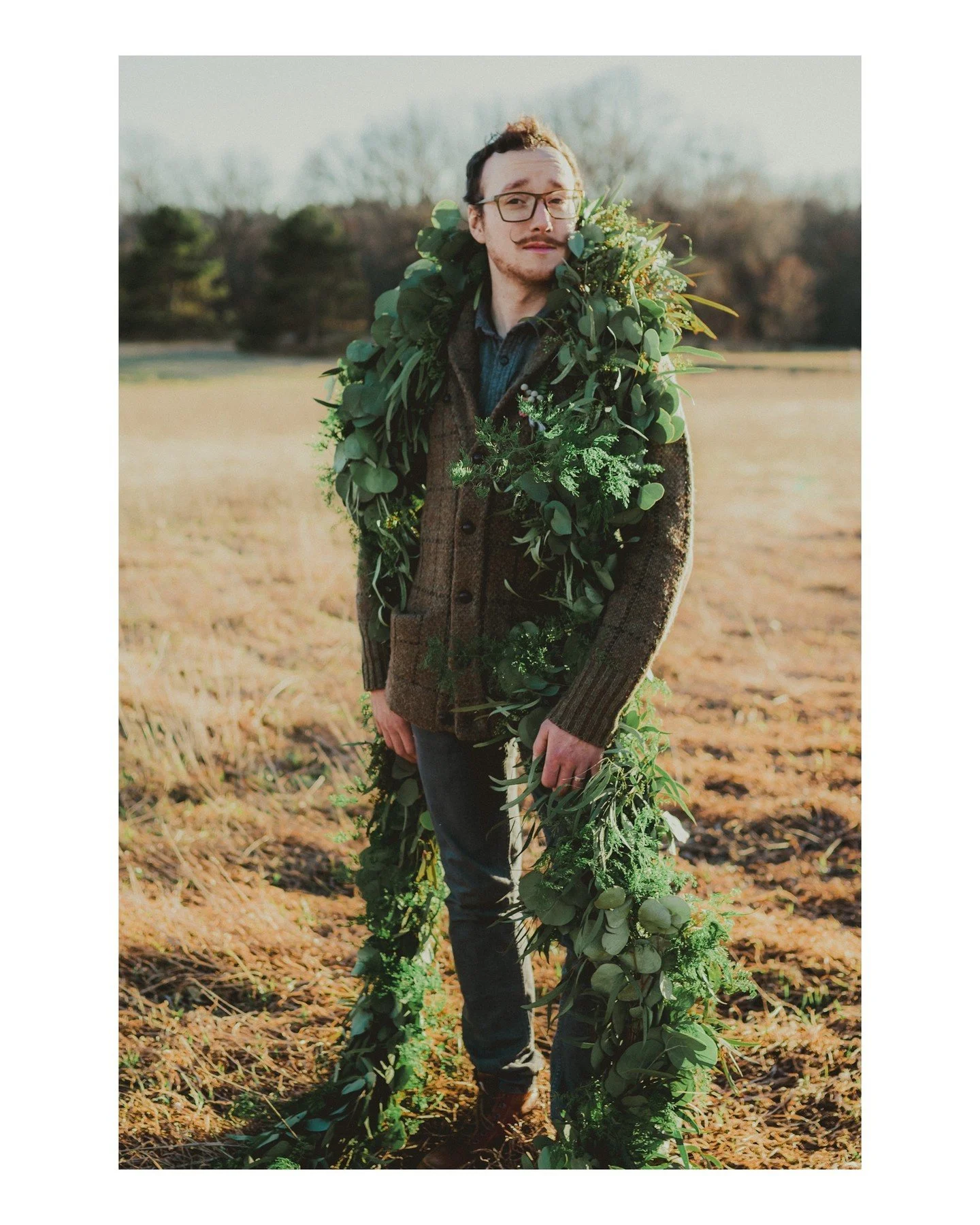 This greenery wreath and sweater combo is one of the most amazing things ever 🤩 I want to see more of this and more braided up-dos for the fellas and masc-presenting folx, please 🙏🏻❤️
.
.
.
.
.
.
[Image Description: A white man with short brown ha