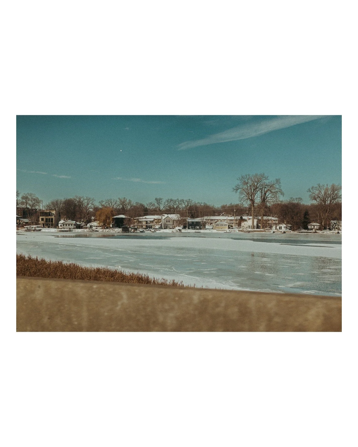 What do we think.... are we finally coming to Spring? 🫣 
.
.
.
.
.
.
.
[Image Description: A landscape featuring an aqua blue sky a wheat field, and a frozen lake, in Monona, Wisconsin.]