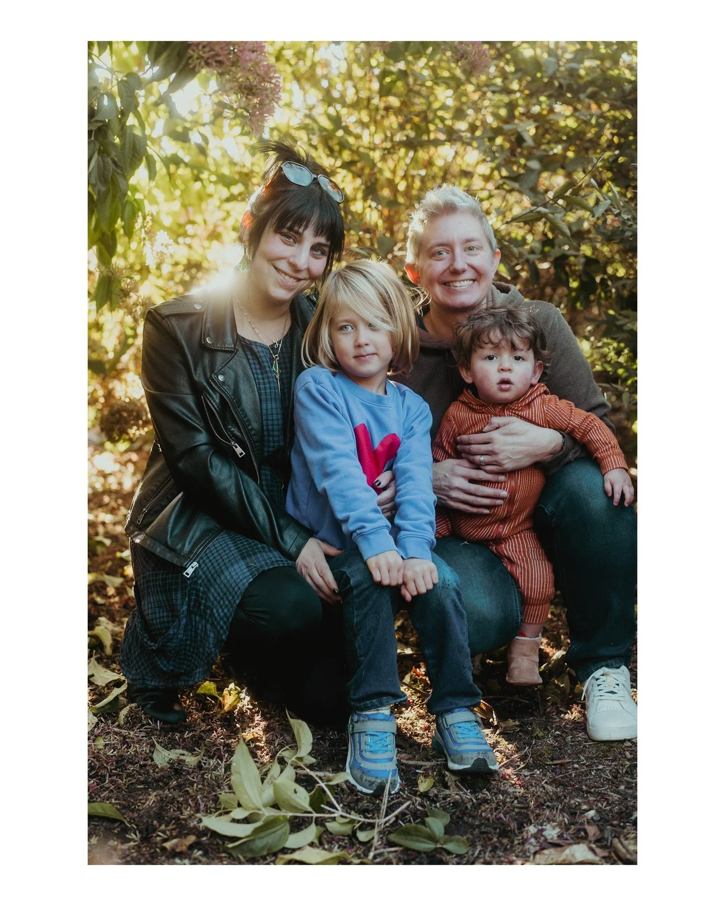 If your photographer isn't showing families that look like yours, they're not the one, babe. 💜🏳️&zwj;🌈🏳️&zwj;⚧️
.
.
.
.
.
.
[Image Description: A white woman with black hair and bangs, wearing all black, has a 4 year old girl sitting on her lap. 