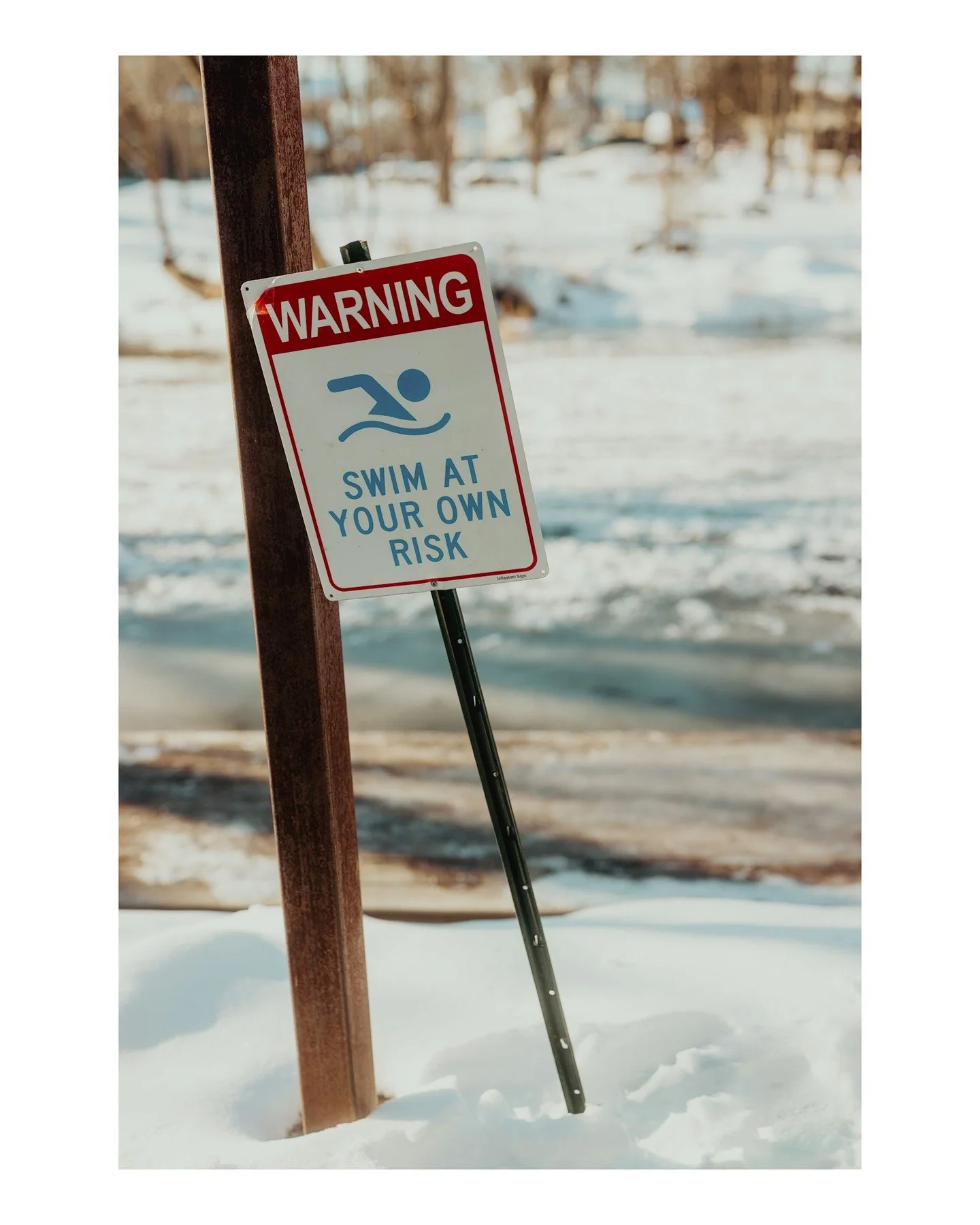 I love Wisconsin 😂🏊🏼
.
.
.
.
.
.
[Image Description: A winter scene next to a frozen river, with a sign in the foreground that says "Warning: Swim at your own risk".]