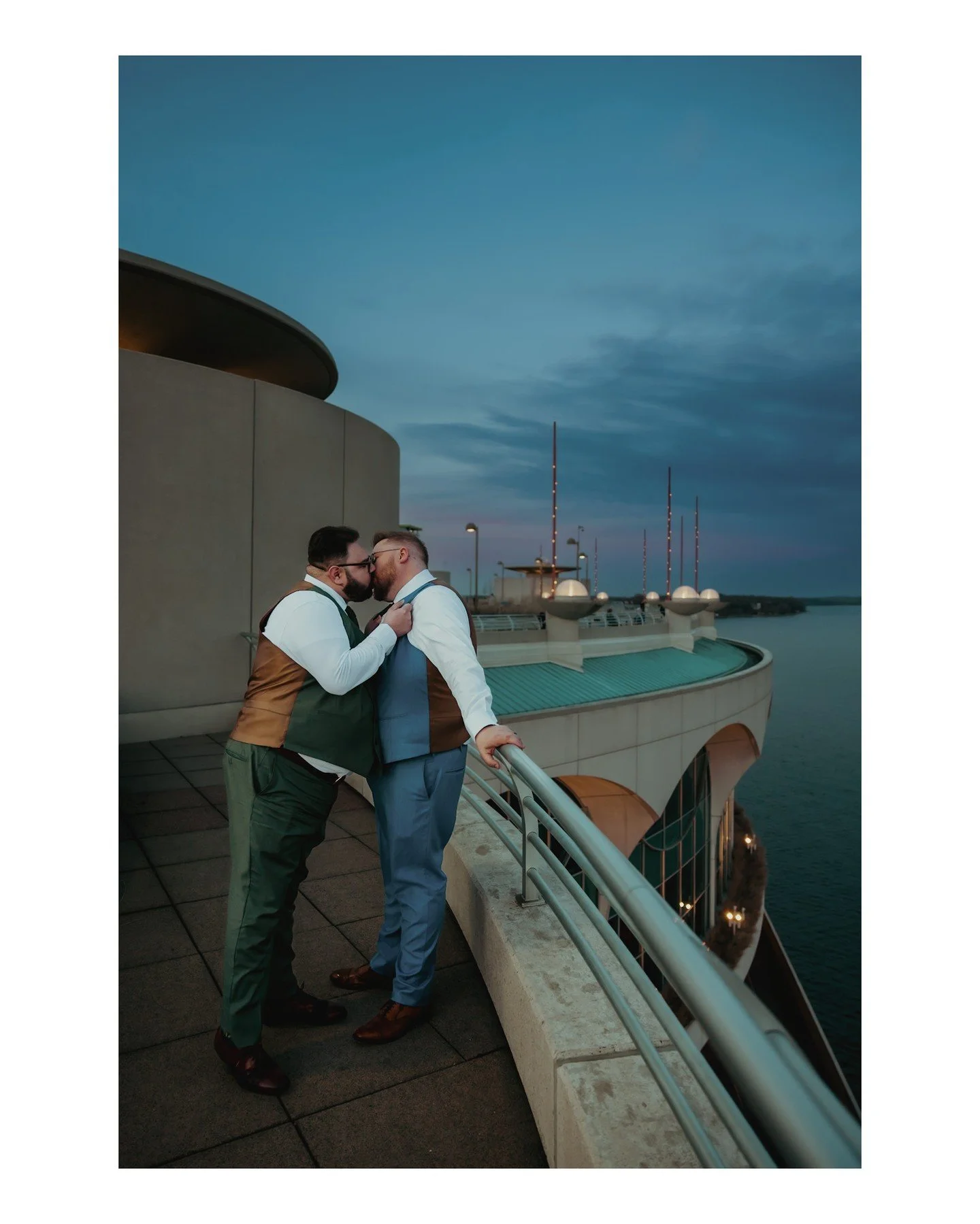 This shot of Alex + David is so dreamy 😍 I love the dusk skies, the aqua blue of the water, and the entire scene as we photographed these two at sunset! 
.
.
.
.
.
.
[Image Description: Two grooms, one with dark brown hair and a dark sage colored pa