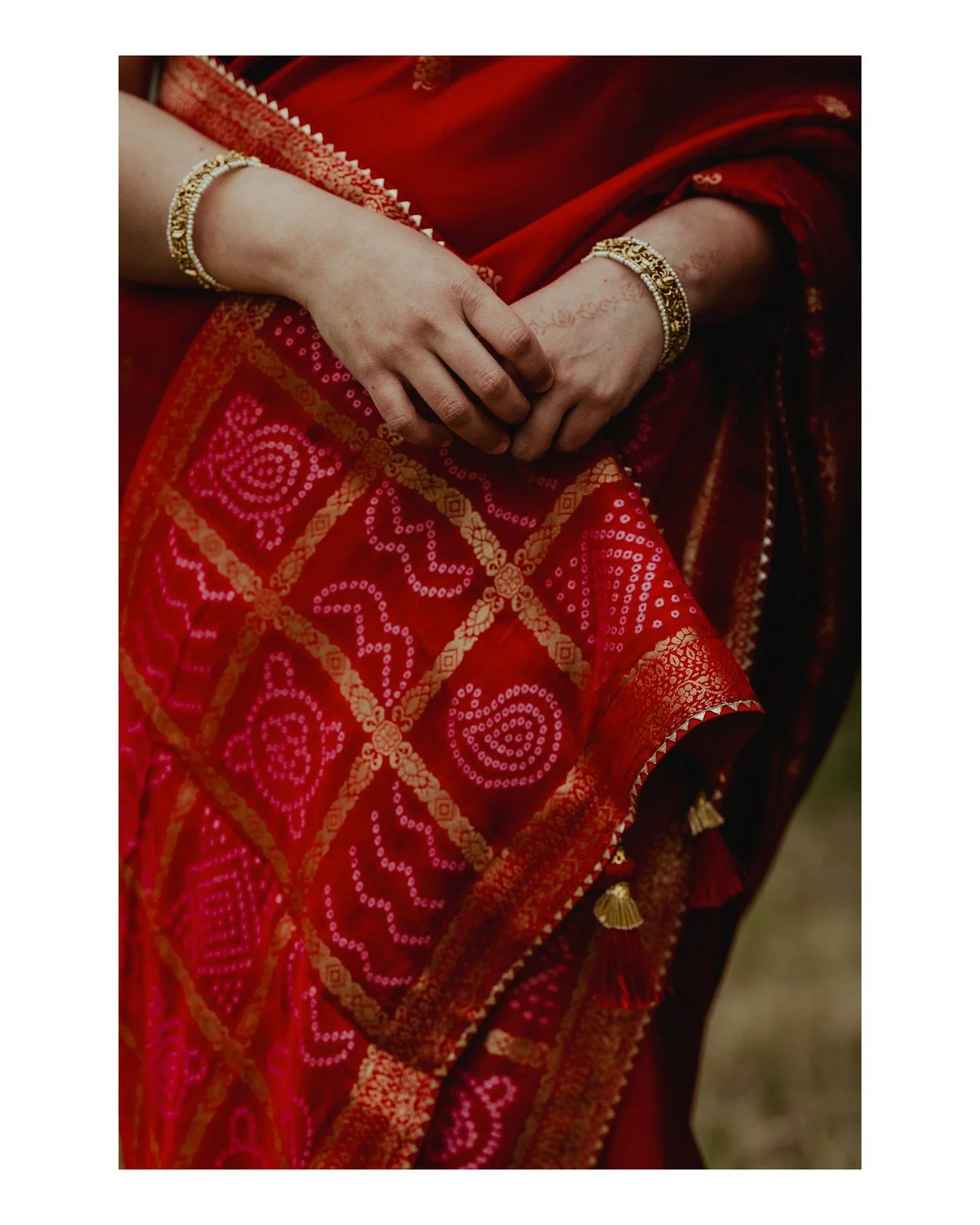 Stop what you're doing and look at this beautiful close-up of Pree's wedding dress &amp; jewelry 😍
.
.
.
.
.
.
 - Camera Gear: 
 - Canon: @canonusa
[Image Description: A close-up image of an Indian woman's hands in front of her red &amp; gold weddin