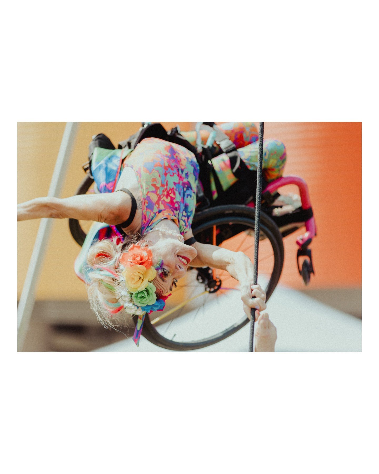 I LOVE this photo of the wheelchair aerial set at the @outreachlgbtqmadison Magic Pride Fest 😍 The colors, the feats of strength, the joy, I love ALLLLL of it! 
.
.
.
.
.
.
[Image Description: A close-up image of a white person with blonde hair wear