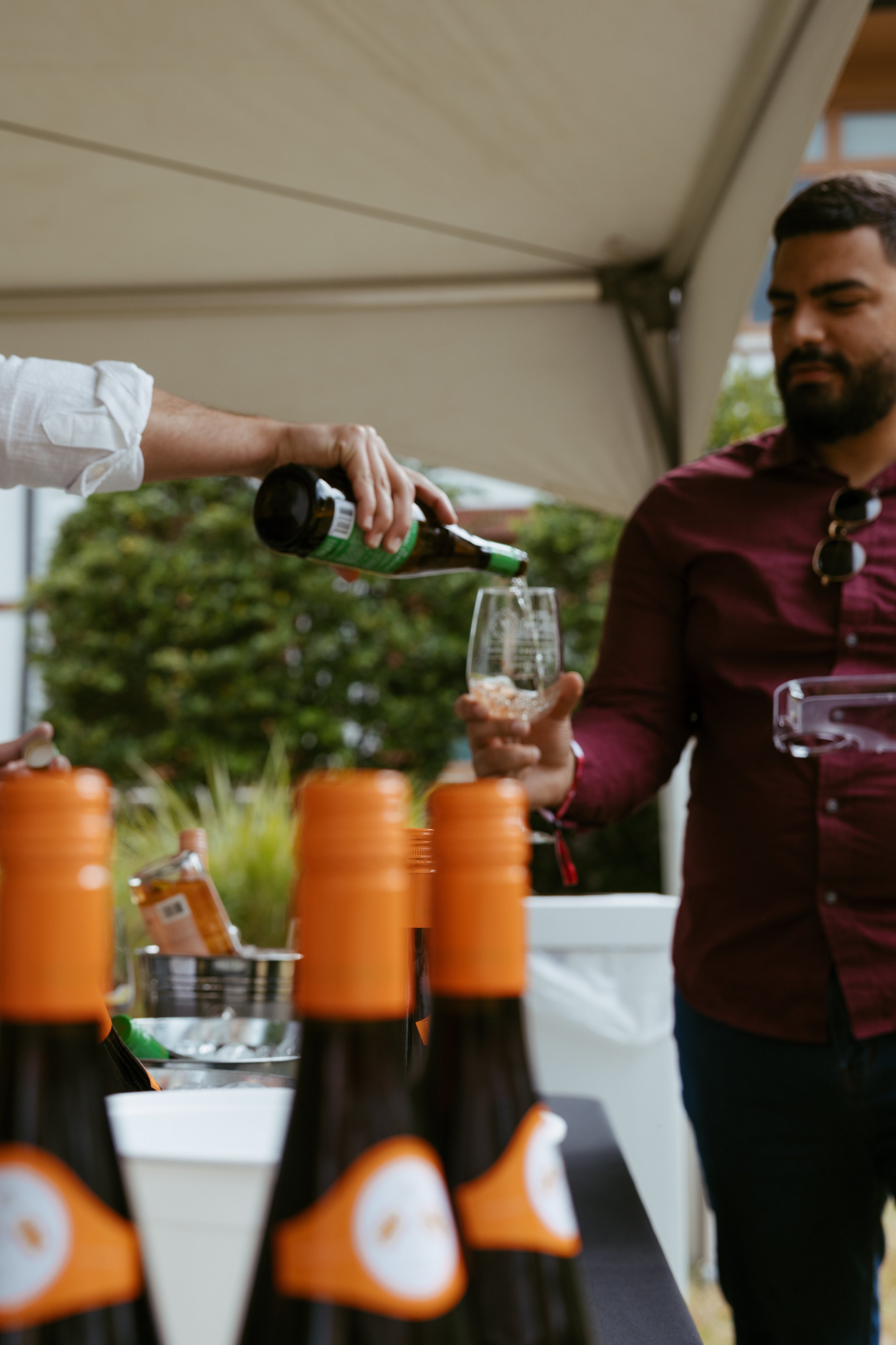 People at outdoor wine tasting event with bottles displayed on a table