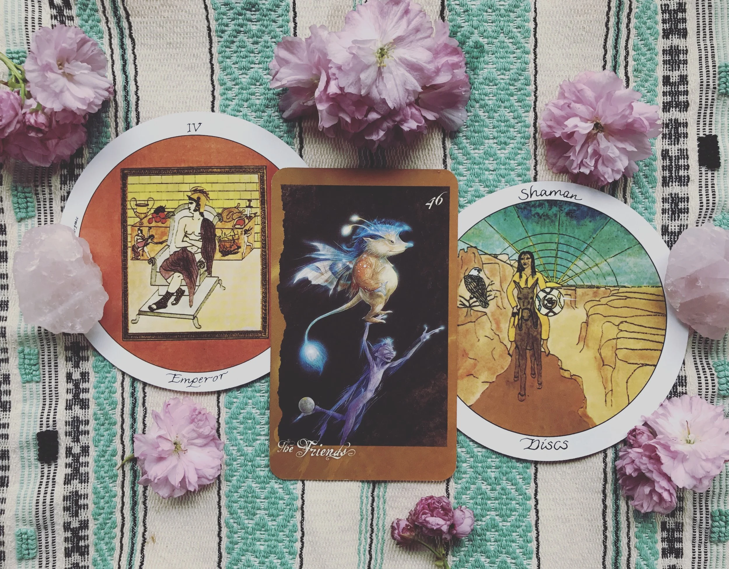We all get by with a little help from our friends. You may have noticed that I drew the 3 of cups two days in a row, a very friendly card. I’ve been in, and only occasionally out of, a sort of closed off introvert mode for the last year and a half. For those who know me, you know that is not my norm. I’ve always been an extrovert. In hindsight, I needed that time. I don’t think I’ll ever go back to being a full on extrovert ever again. But lately, I am being drawn back out and into the world of people and friendship, but not in the same way as before. This draw reflects and teaches the wisdom of being able to enjoy, connect, support, and cooperate with others while also remaining balanced in yourself, with your own needs, and purpose. Keeping this balance is tough, as our needs (and the needs of our loved ones) are ever-changing and there isn’t really a set schedule or we can keep or consistent methodology we can apply. Fortunately though, there are some lessons we can keep in mind to help us navigate our complex social landscapes. Motherpeace’s interpretation of the emperor shows him as a rigid, authoritative, defensive, afraid to open up to any other possibility for it may threaten the fixed ideology he has built his world within. I’m not going to lie, while I was doing my shadow work and deep healing, I felt very defensive and it is part of what kept me at arms length from most people. But it was also, the rigid thinking of others that made them hard to bear. The Shaman of Disks is at ease alone and with people. She doesn’t falter either way. Because she is well aware and committed to her dharma (her life’s work and purpose), this knowledge offers her the stability, balance, and leverage to stand strong within her own boundaries, while still offering support, love, and companionship. She knows what is most important to her and the influence of others isn’t going to shake her core, unless of course it is a lesson she needs. Her lesson is much the positive alternative interpretations of the emperor, who is able to stand in his own authority and set boundaries that he and others follow. Truly, the key to balance comes down to having a solid sense of self and an understanding of your own value. And that is something I think I had to go into the dark to find: something I am still finding. Yes, my lack of boundaries were being taken advantage of in the past. But more than that, when I came up against opposition from the people I loved, it would strike me right in the gut. If they didn’t agree with me how could I be right? How could my knowledge and beliefs be worthy if they did not share them or value them? And as I stepped into my magic and spirituality this issue blew up. As many of my co-healers know all too well, there are some people that will never understand. I was looking to others to validate myself and my beliefs. And that is what resulted in the skewed balance that had me run into my own dark cave for a while. For you it may be that you give too much of yourself with little love in return. It may be that you fear opening up to others. Whatever it is, we have to understand that healthy friendships and social interactions require balance and it starts within. Blessed be.