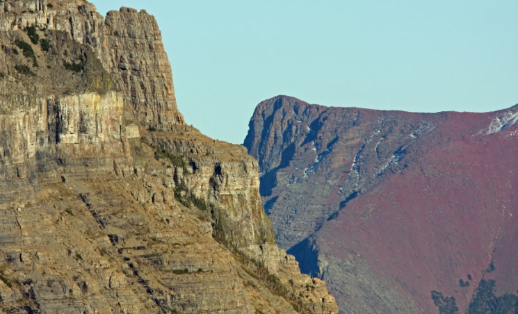 The Empire formation of Going-to-the-Sun Mountain contrasts with the red Grinnell formation of Red Eagle Mountain in Glacier National Park.