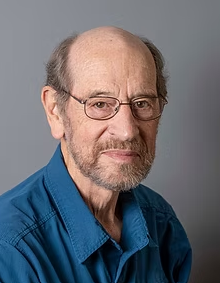 Portrait of Peter Cavanagh with glasses and a beard wearing a blue shirt