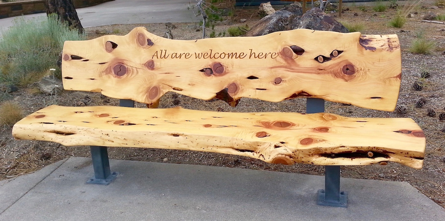 Photo of the "All are welcome here" bench at the entrance.