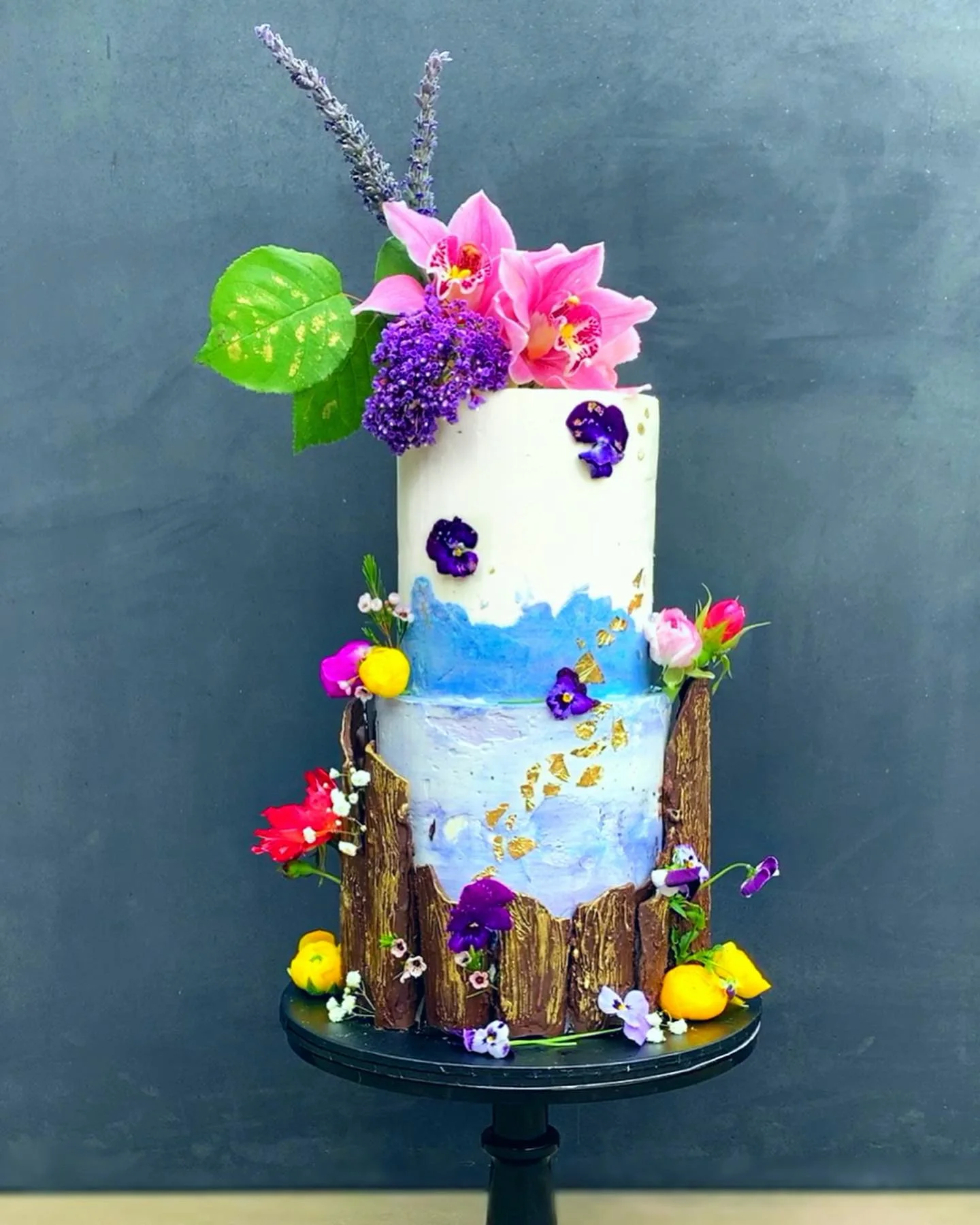 Watercolor buttercream cake with chocolate bark adorned with fresh florals