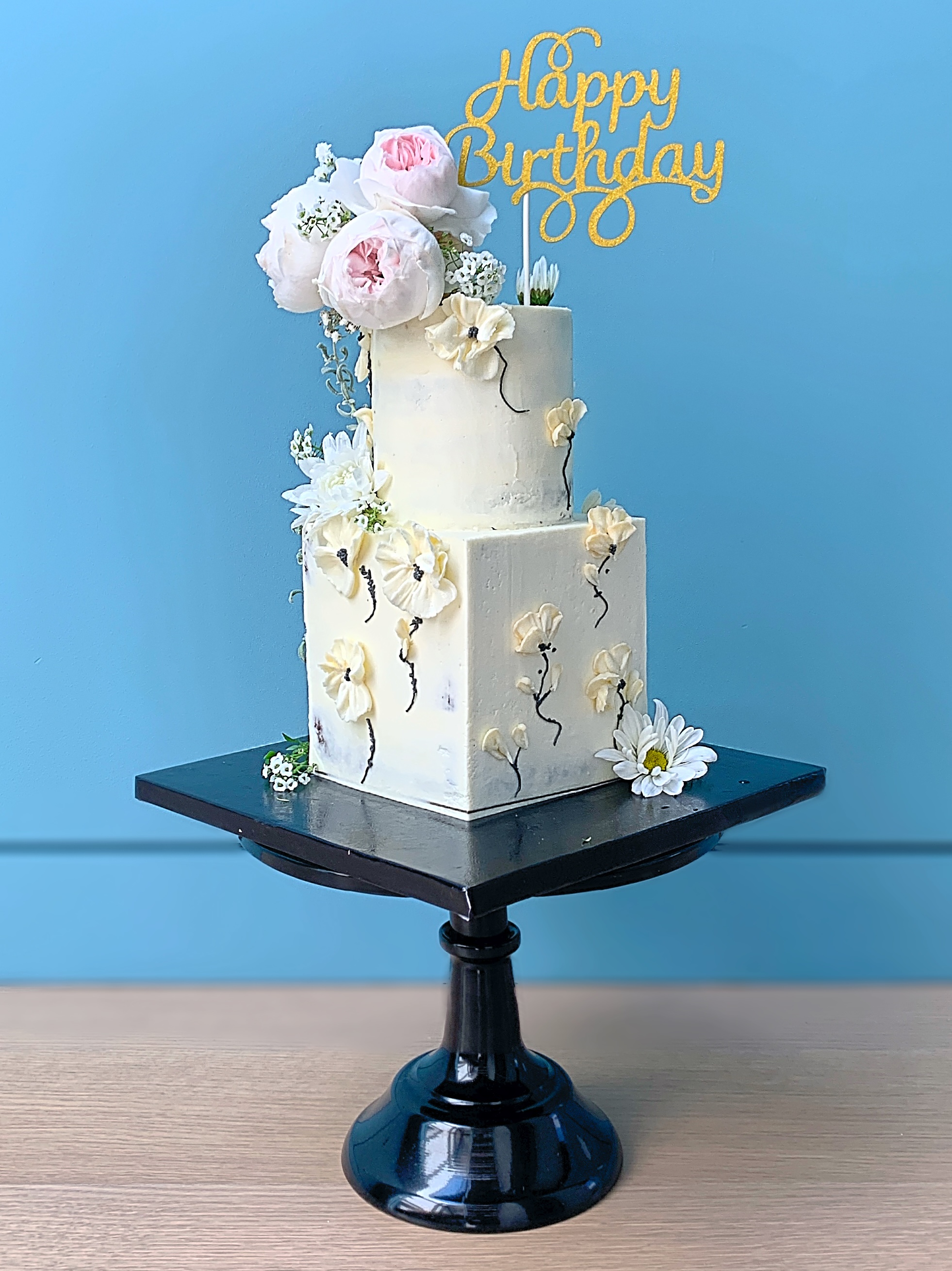 Buttercream cake with hand piped florals and adorned with fresh flowers
