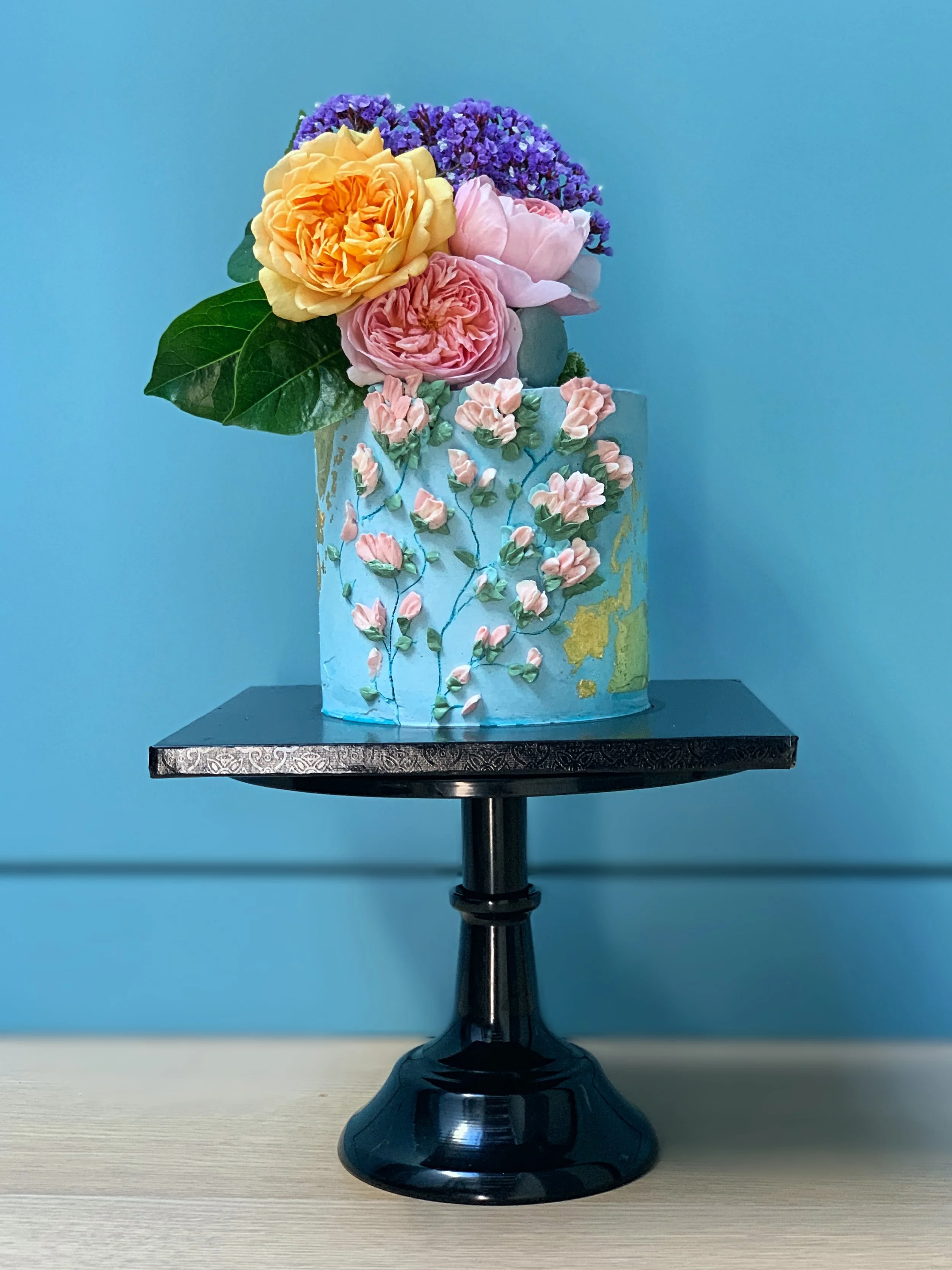 Piped floral buttercream cake adorned with fresh flowers
