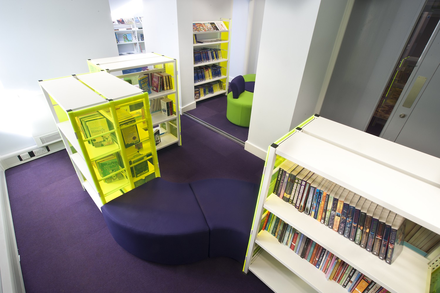 Soft seating pads positioned at an angle between shelving bays.