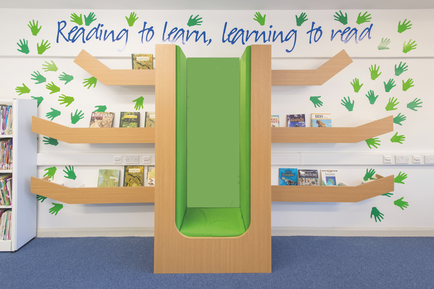 Woodland themed reading booth with vinyl hand prints in shades of green, mimicking tree leaves.