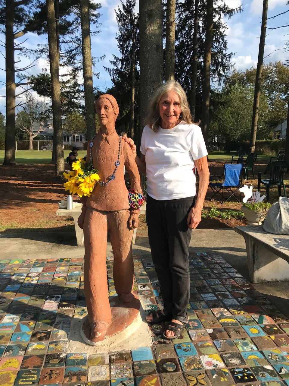  Sculptor Sally Laird McInerney poses by her beautiful Peace Pilgrim likeness, which was re-installed just in time for the celebration after she repaired it from extensive damage caused during a storm when a tree fell on it.  