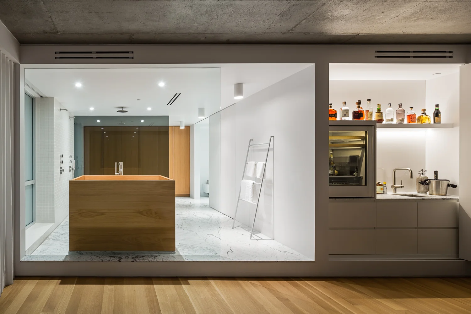 Wooden floor stumbling on a podium where is deposited the bathroom of the masters. Large statuario marble floor with double bath in white oak. Concealed mini bar