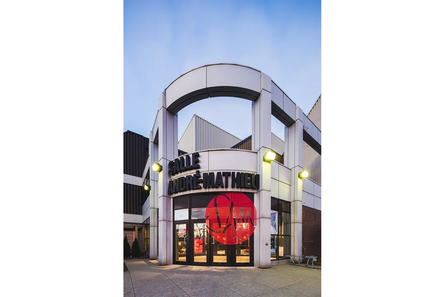 Vue de la façade principale de la salle André-Mathieu à Laval. Intégration du nouveau logo dans la vitrine. Pastille rouge avec lettrage en négatif.