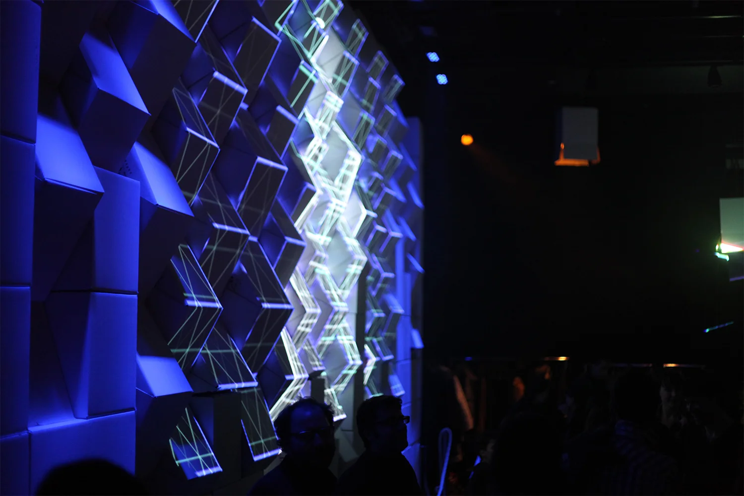 Installation of a wall of cardboard boxes at an angle. Multimedia projection (mapping) on the edges of the cubes. Blue and white projection video