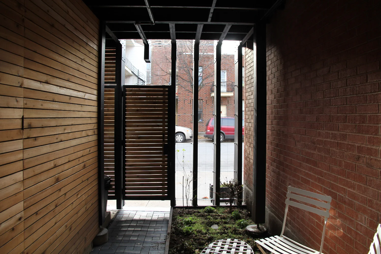 Petite cour intérieur sous la terrasse en bois. Parois de bois et mur de briques rouge