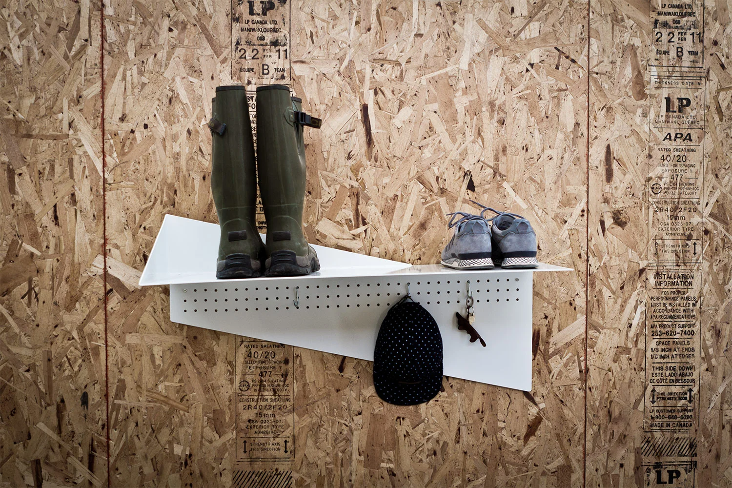 Front view of the finished white lacquered steel tablet. Perforated vertical plate for hanging accessories. Wall shoe rack