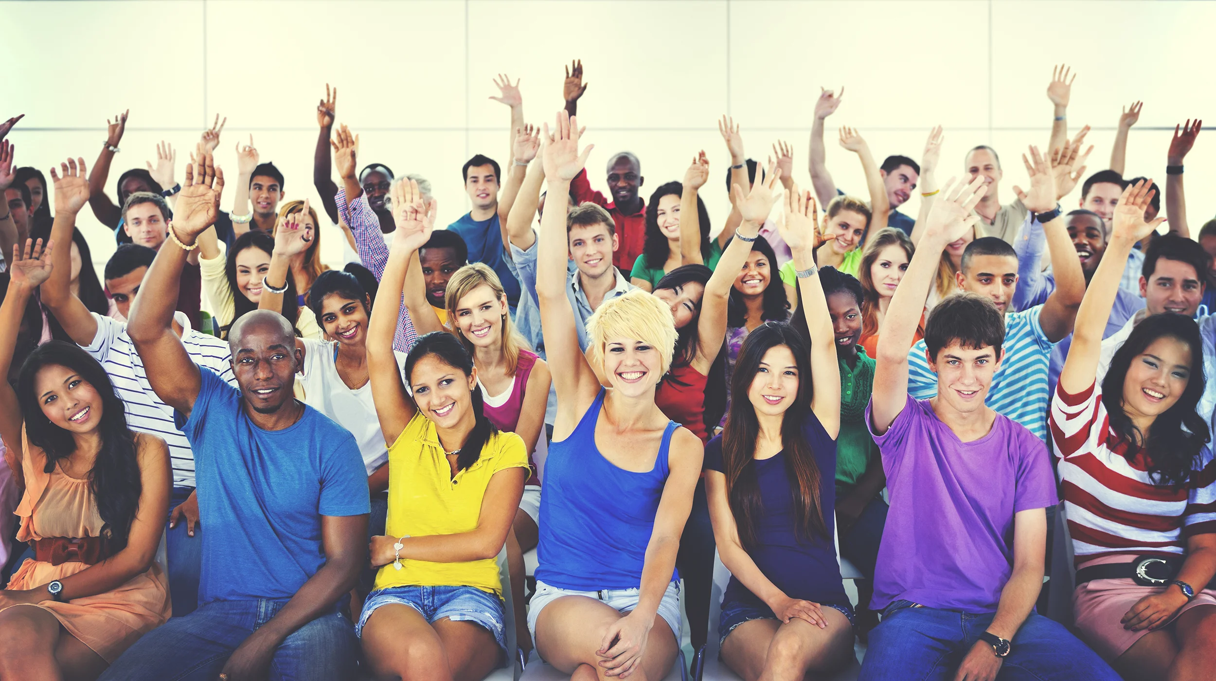 Diverse group of volunteers raising their hands. Bethel ESL teachers are volunteers