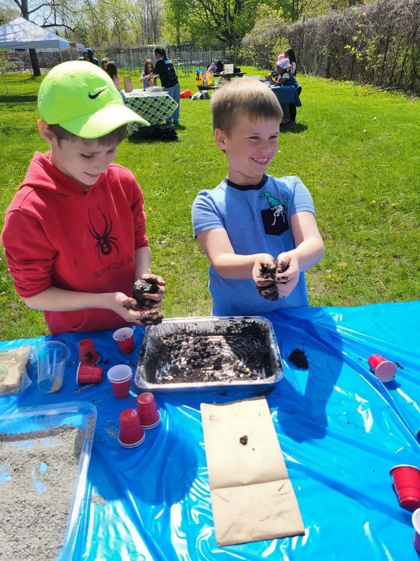 Two young boys making seed balls with mud