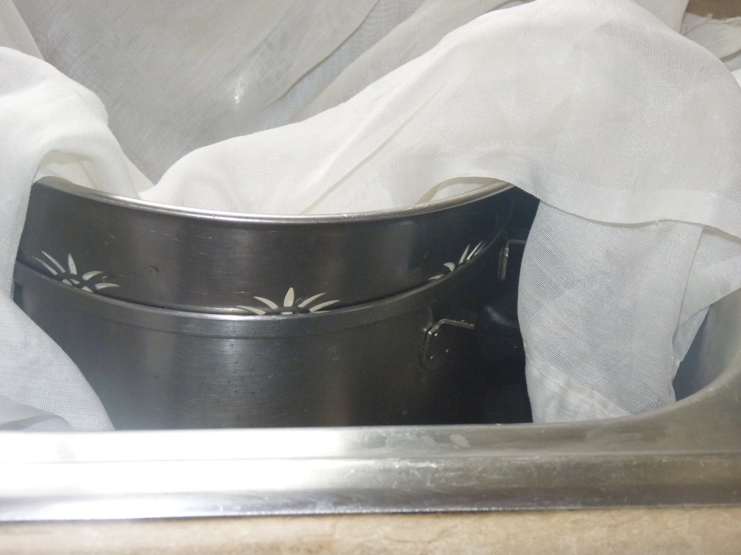 Place a clean, stainless steel pan under your stainless steel colander to catch the whey. Many paneer recipes call for using the whey in the gravy. And you can also add paneer whey to dal or kitcheri for added flavour and protein. Line your colander with a double layer of wetted cheesecloth. (I have found a piece of net curtain works better than actual cheesecloth because it is more finely woven).