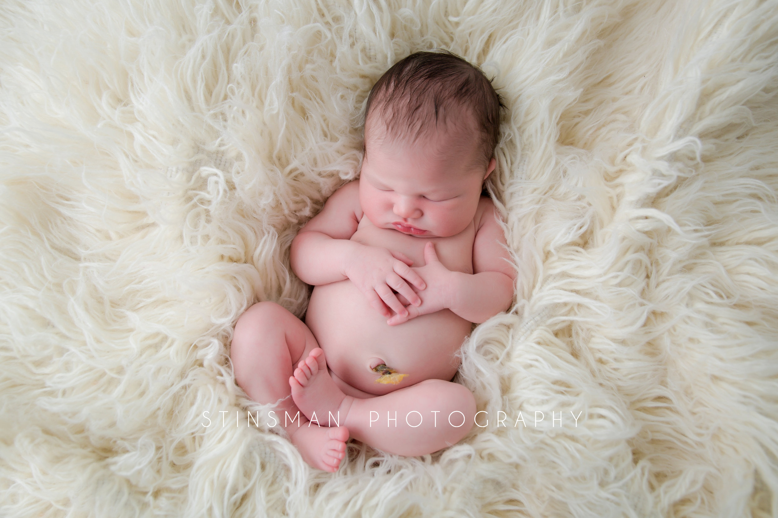 four day old baby girl laying in a cream rug