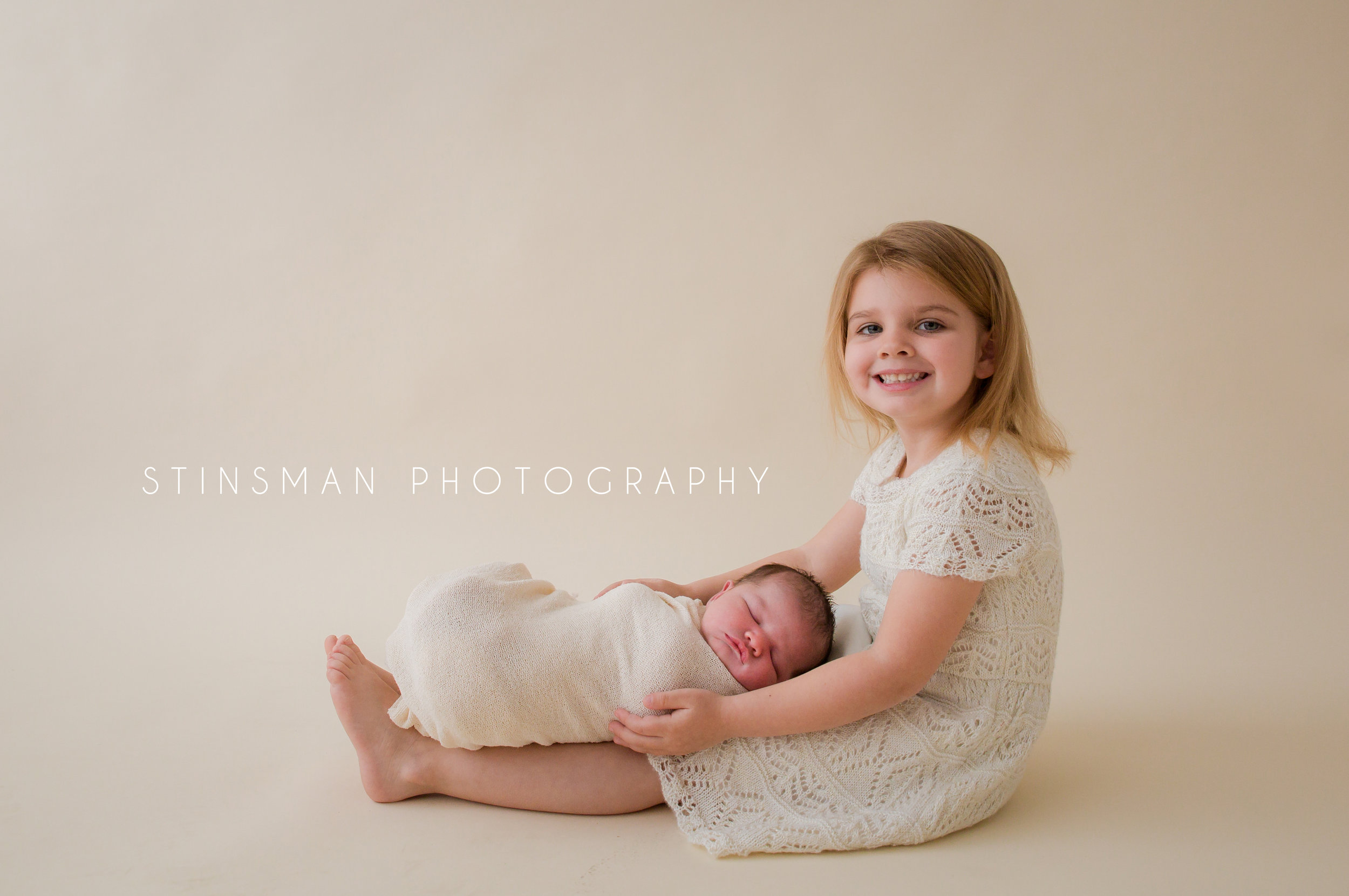 big sister holding her little sister in a cream wrap on her legs