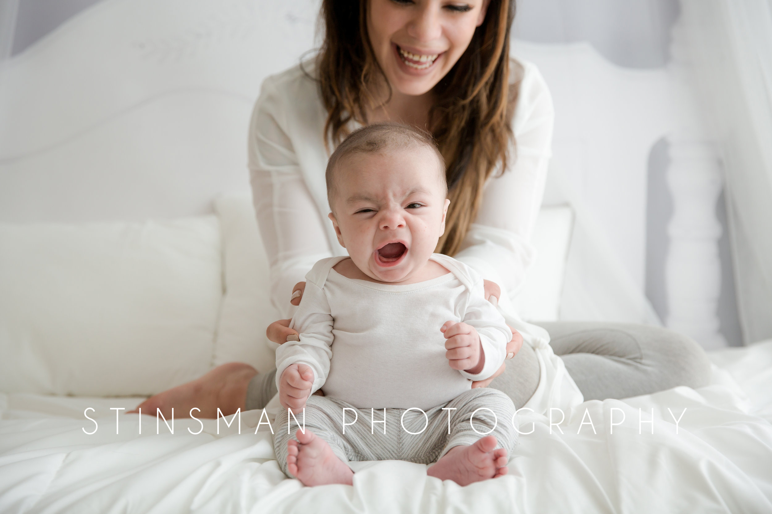 3 month old baby sitting in from of his mother yawning in burlington nj at stinsman photography