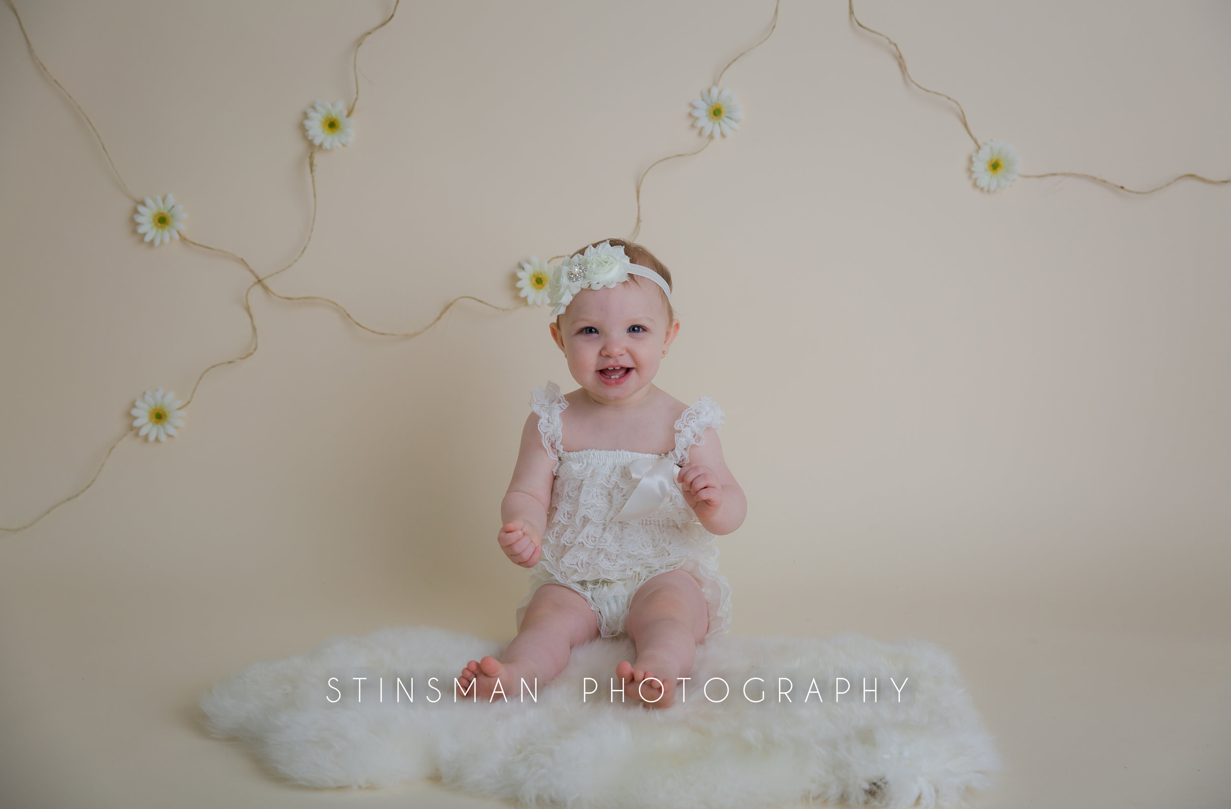little girl photos for her first birthday wearing a white outfit and smiling