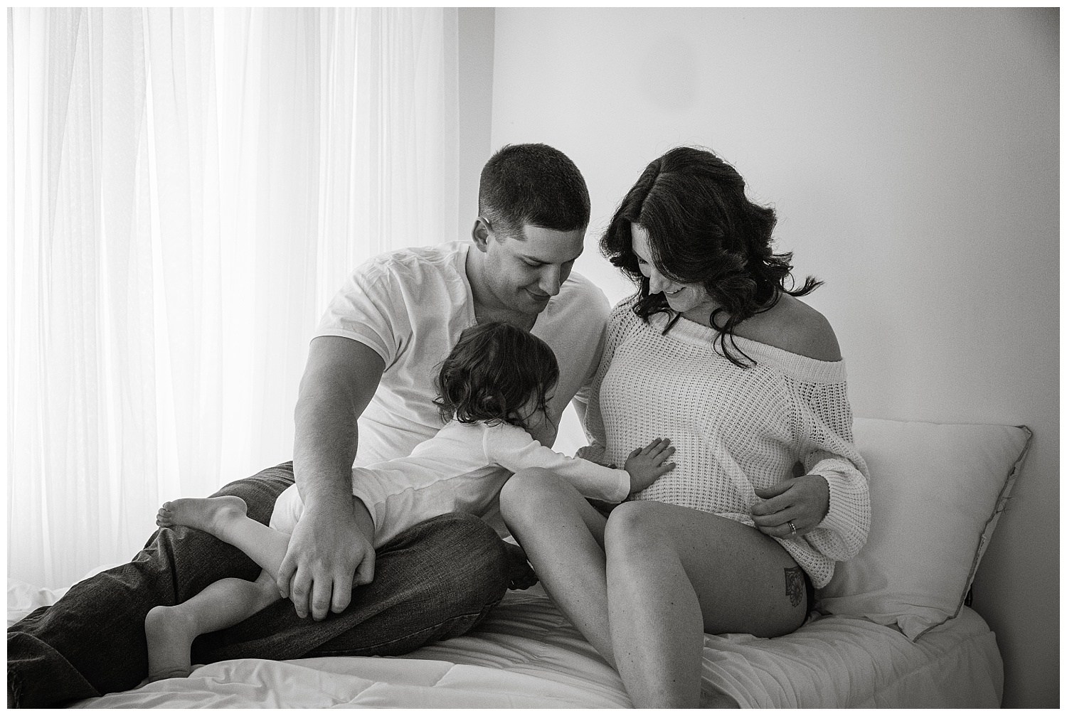 black and white photo of 2 year old holding mom's belly for pregnancy photos