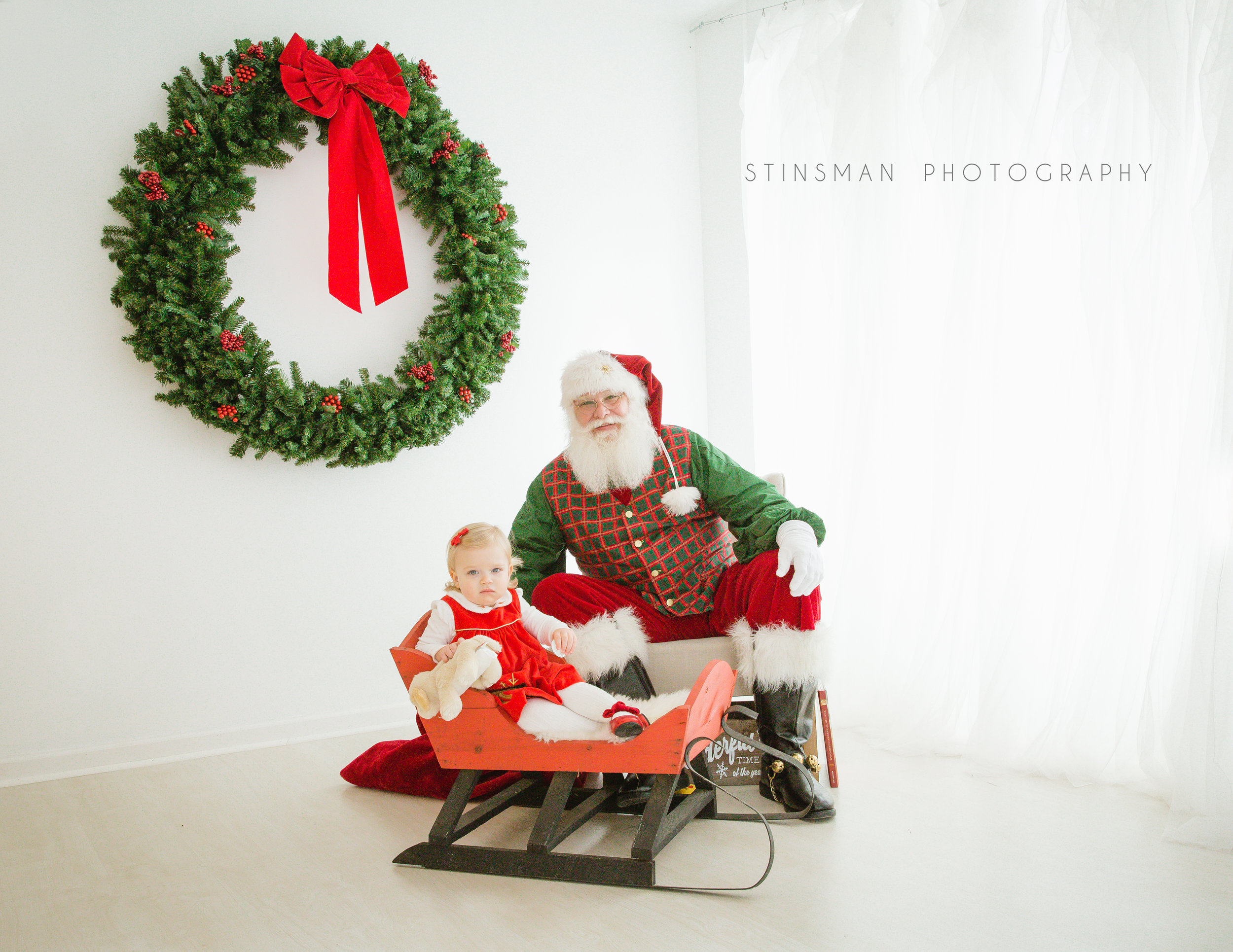 little girl sitting in a sleigh with santa for photos in burlington nj photo studio