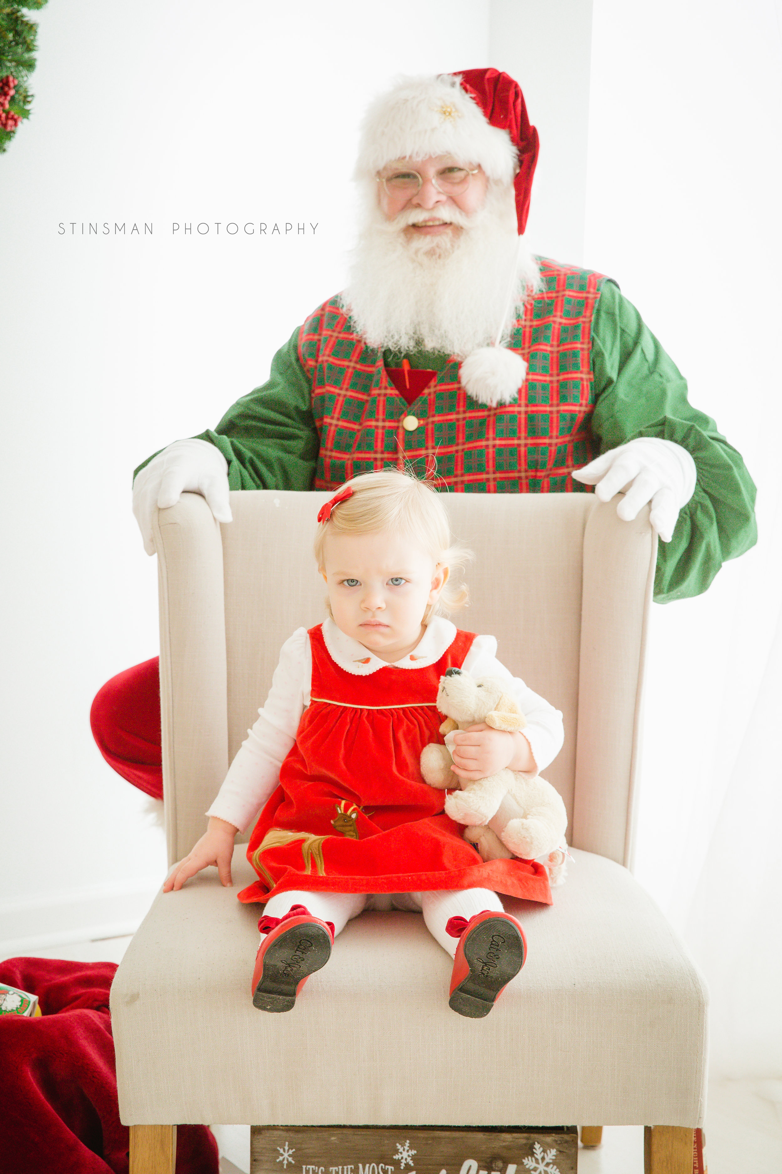 little girl sitting in a chair with Santa behind her in burlington nj photo studio