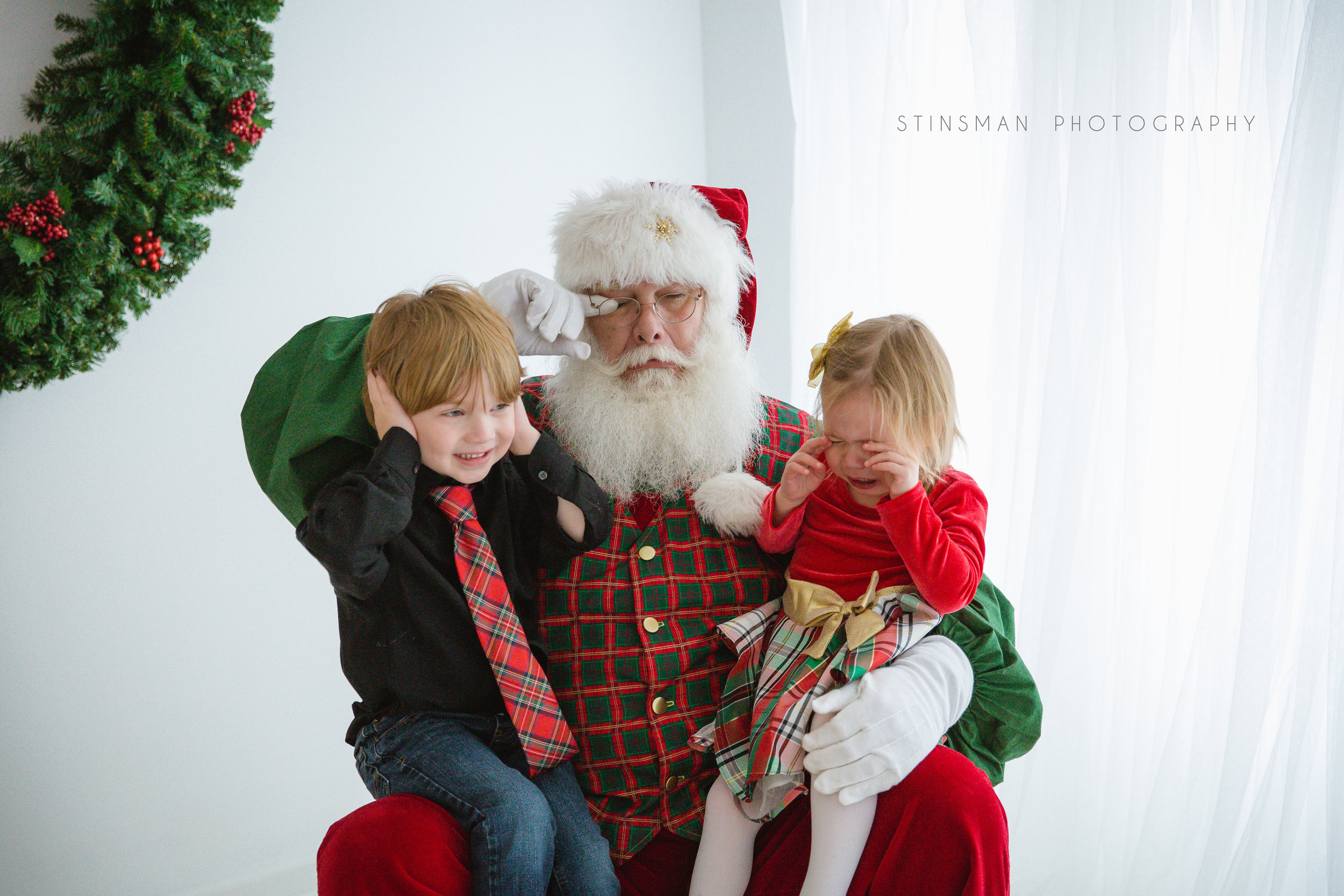 little girl crying while seeing Santa and brother holding his ears in burlington new jersey photo studio