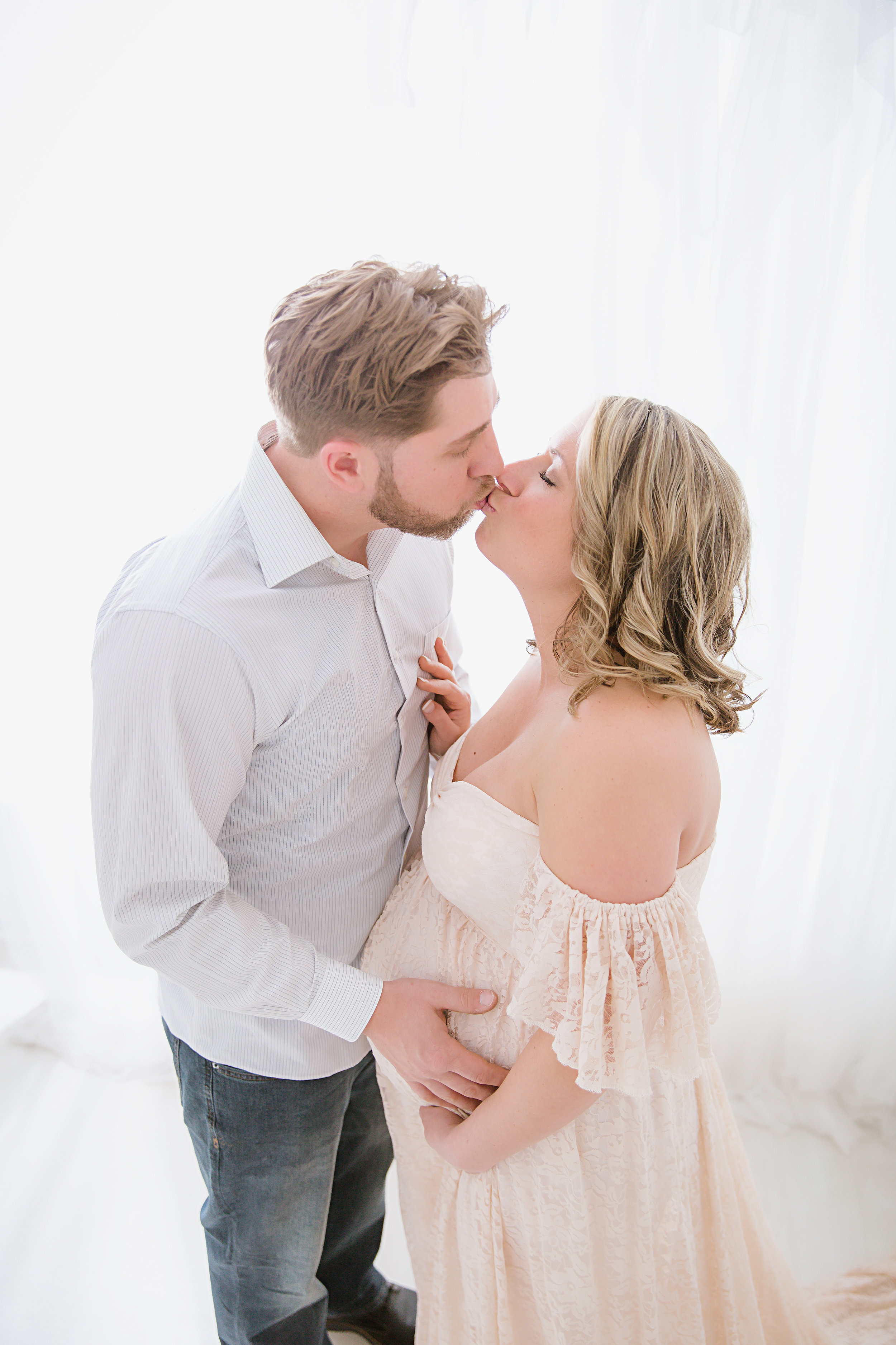 mom-and-dad-kissing-while-holindg-pregnant-belly.jpg
