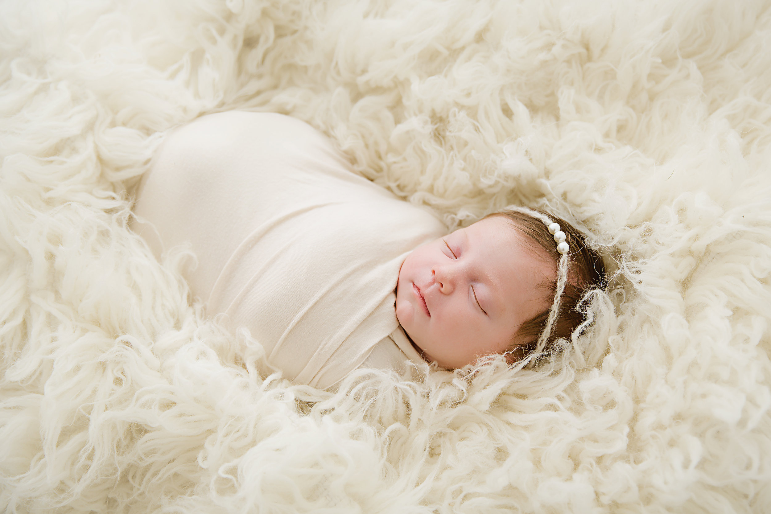 newborn-baby-girl-photography-shoot-wrapped-in-white-lying-in-soft-white-fluff-new-jersey