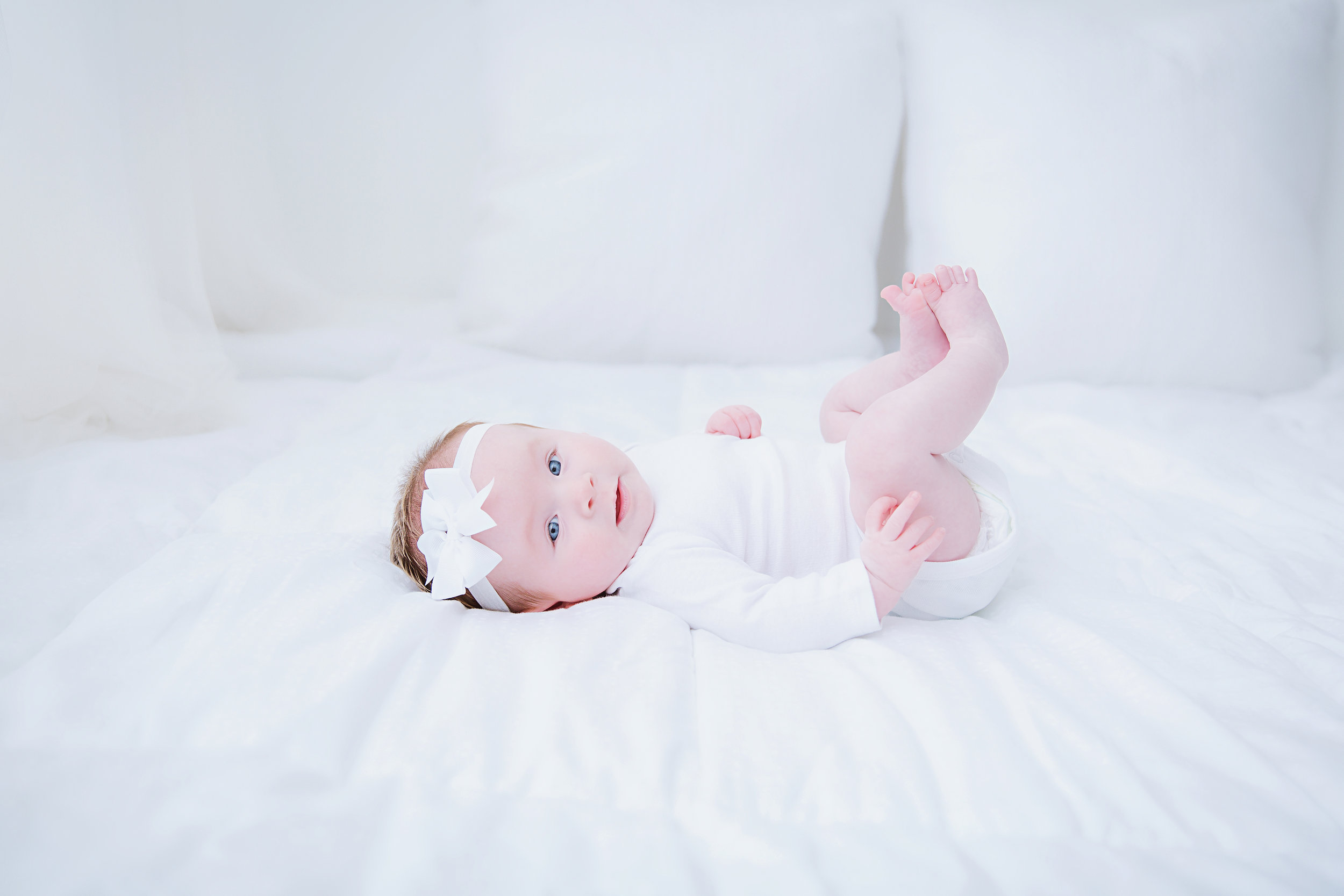 beautiful-baby-girl-photography-shoot-new-jersey-white-bed-white-clothes-looking-towards-camera-new-jersey