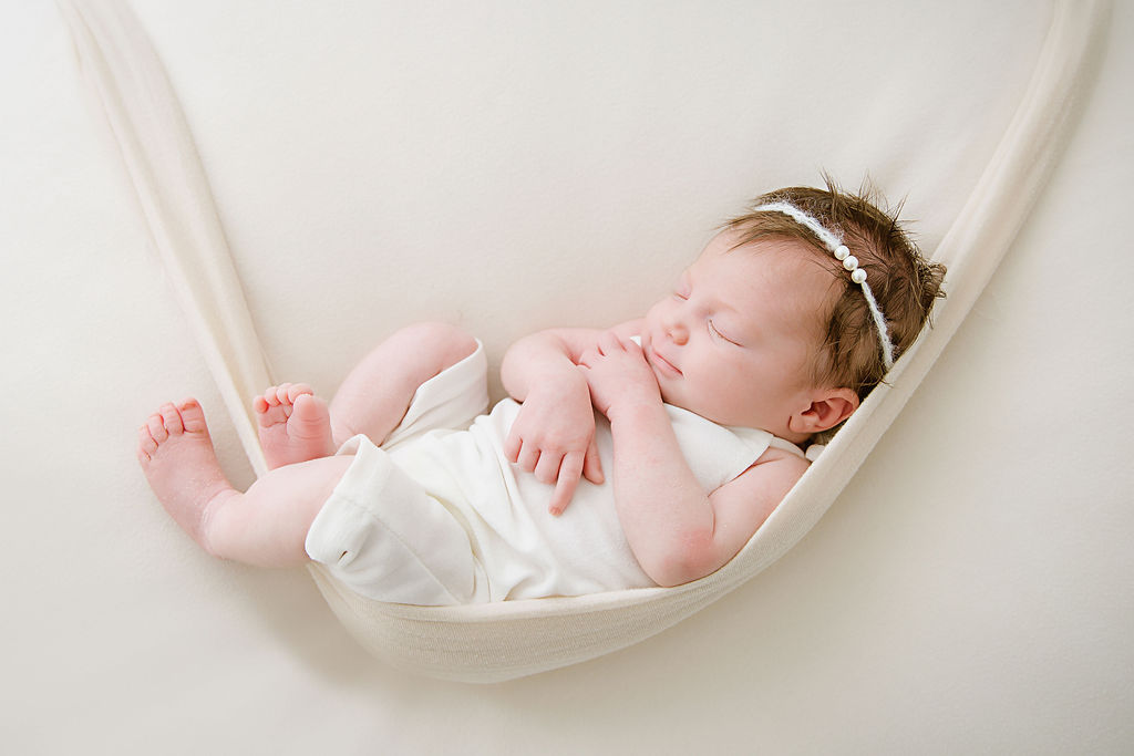 This newborn girl is sleeping peacefully in a soft hammock. Taken by a newborn photographer located in Burlington New Jersey.