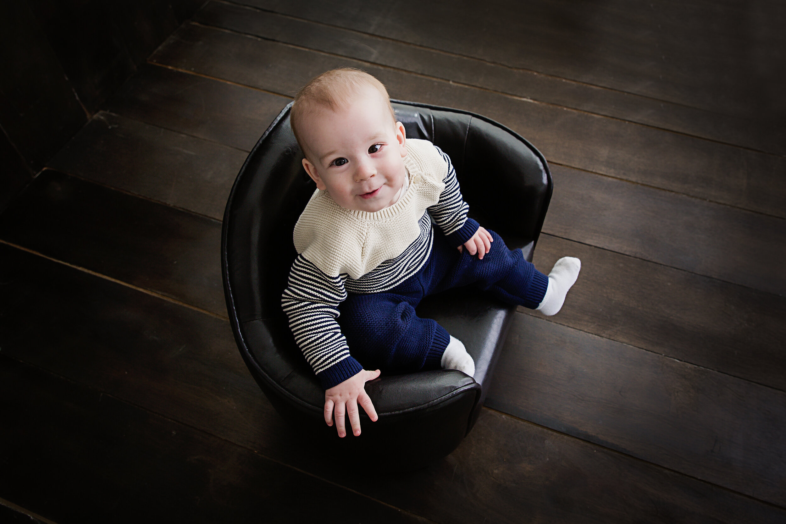 one-year-old-looking-up-at-the-camera-sitting-in-leather-chair