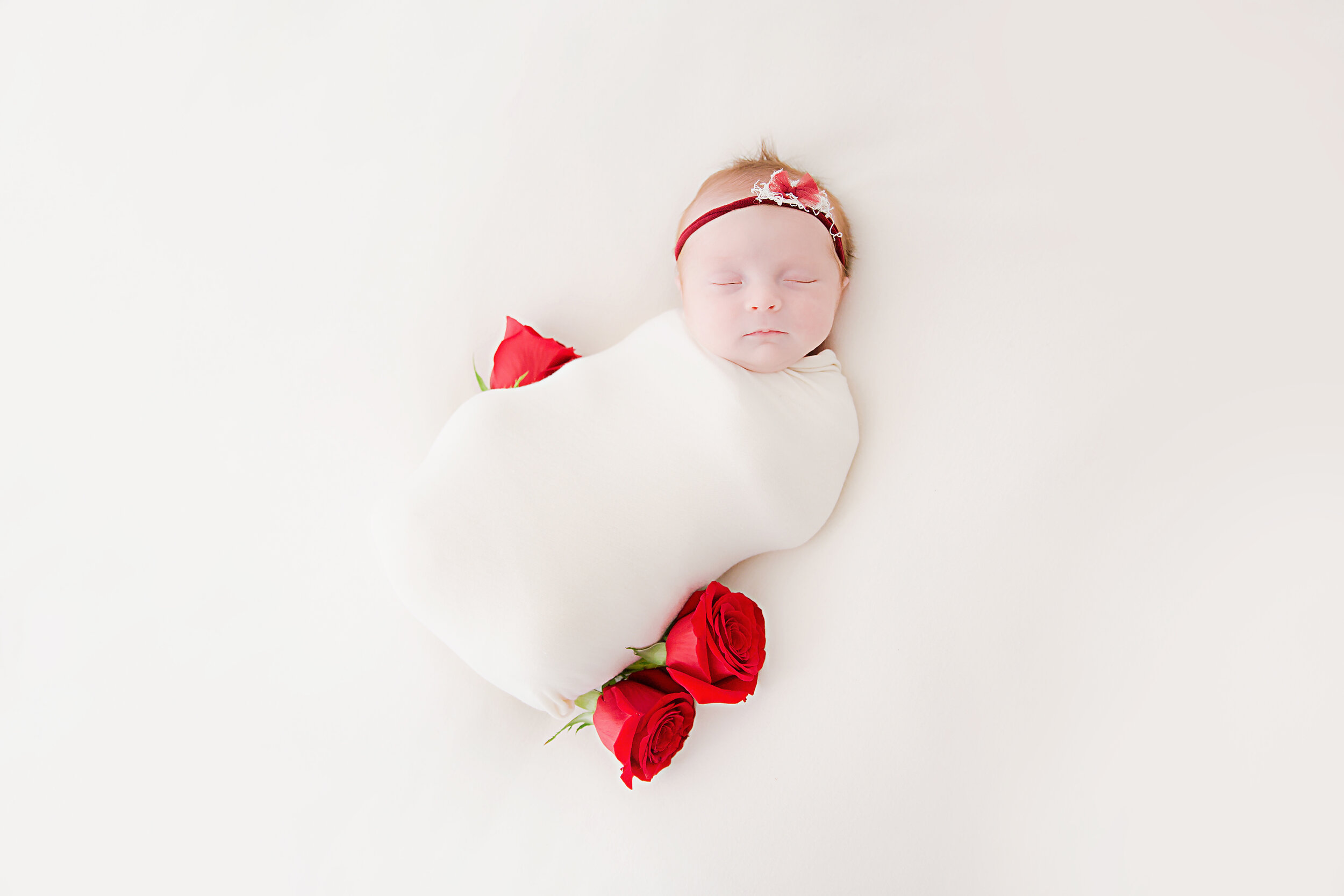 newborn-baby-girl-swaddled-and-surrounded-by-roses