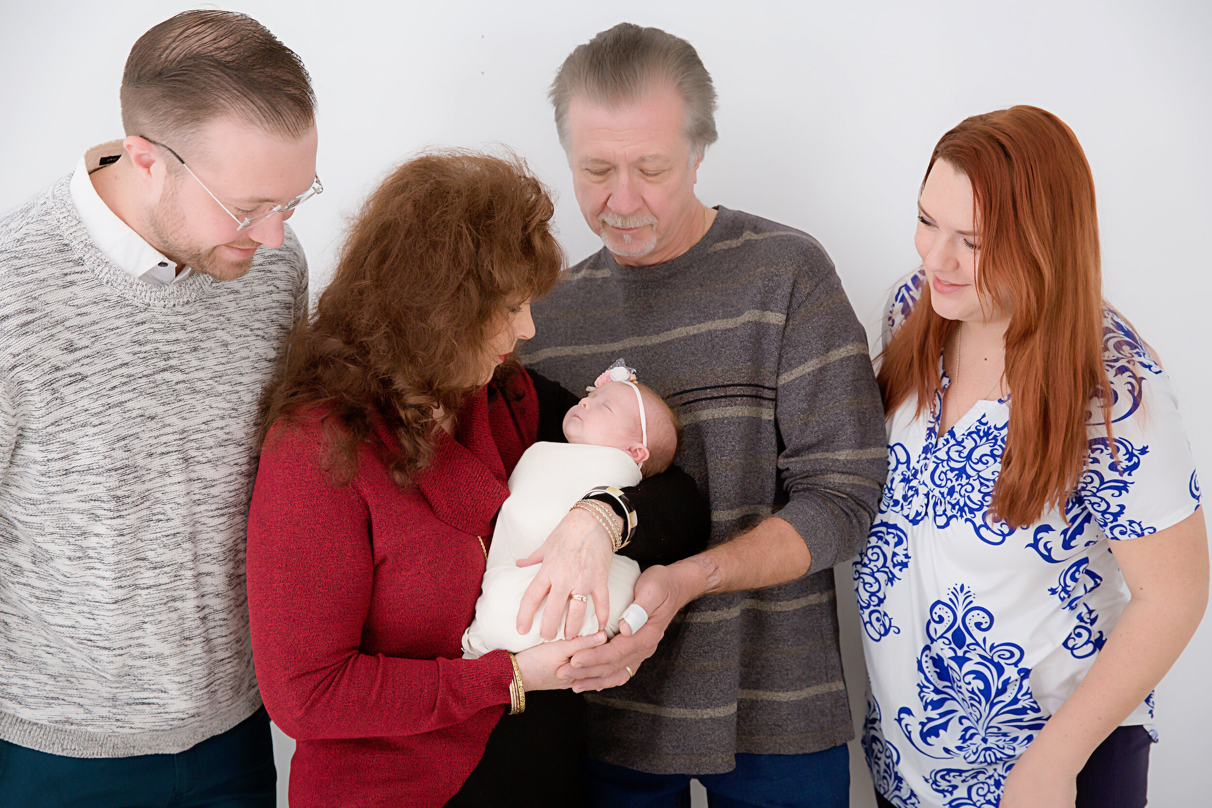 newborn-baby-girl-being-held-by-grandmother-and-other-family-members