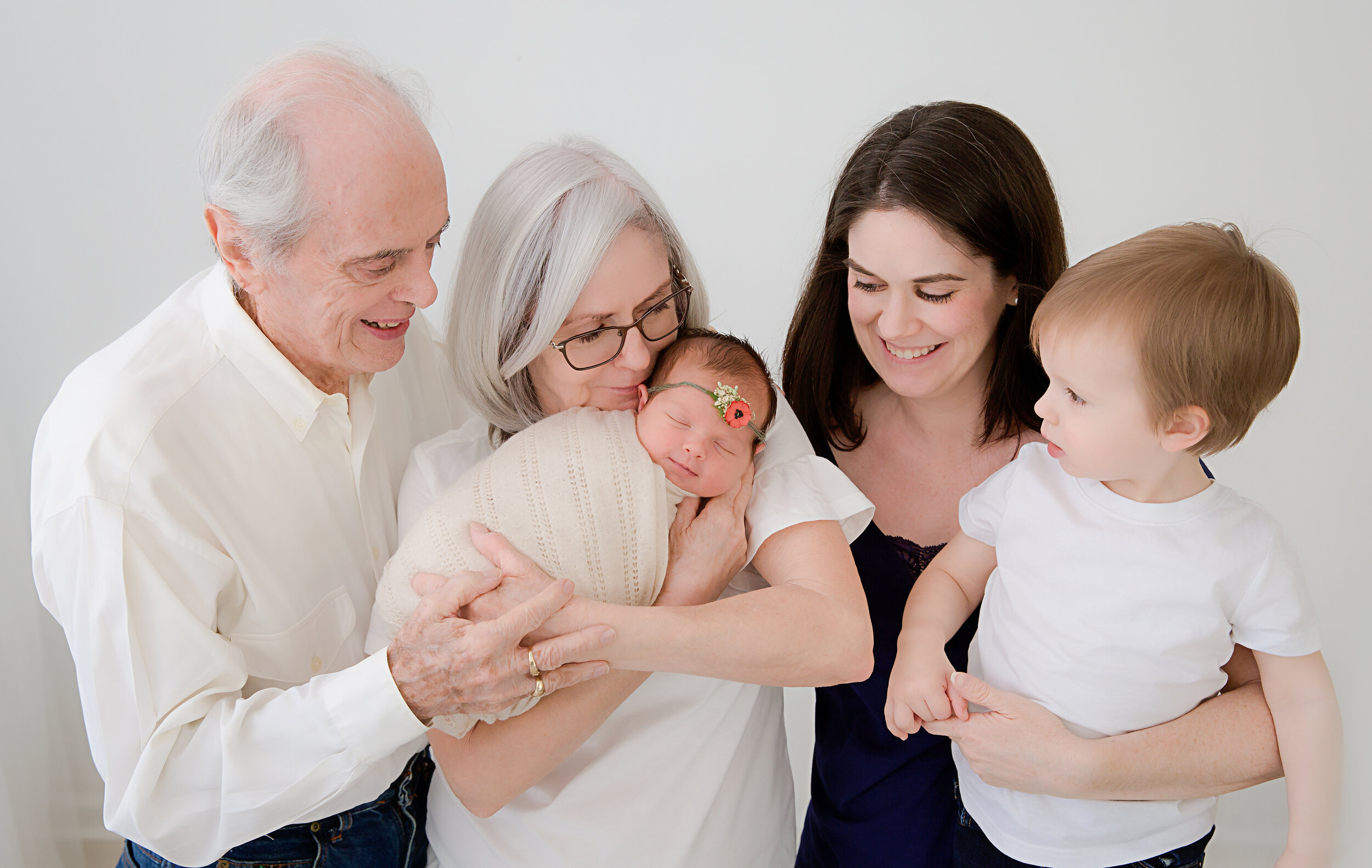 grandparents-holding-baby-standing-next-to-mom-and-big-brother