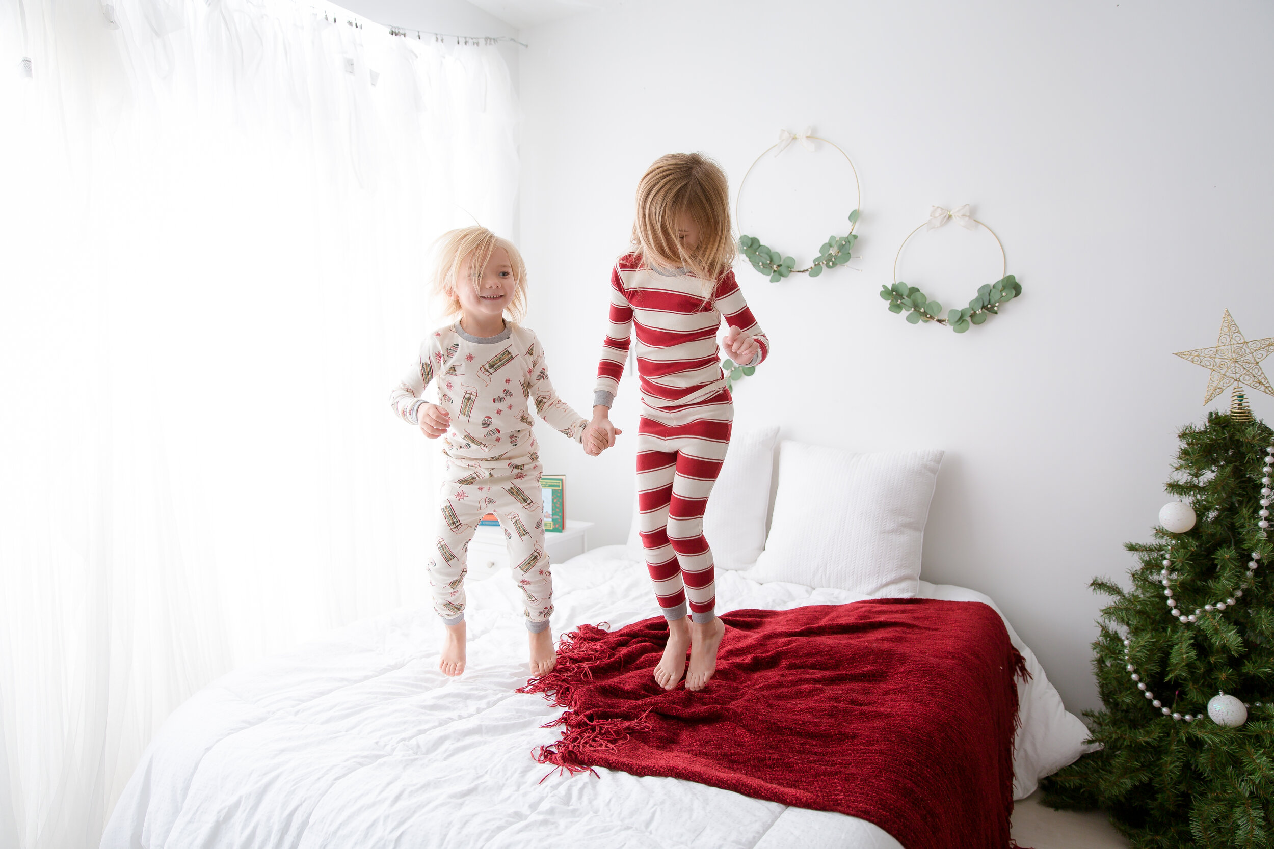 sibilings-jumping-on-bed-in-christmas-pajams