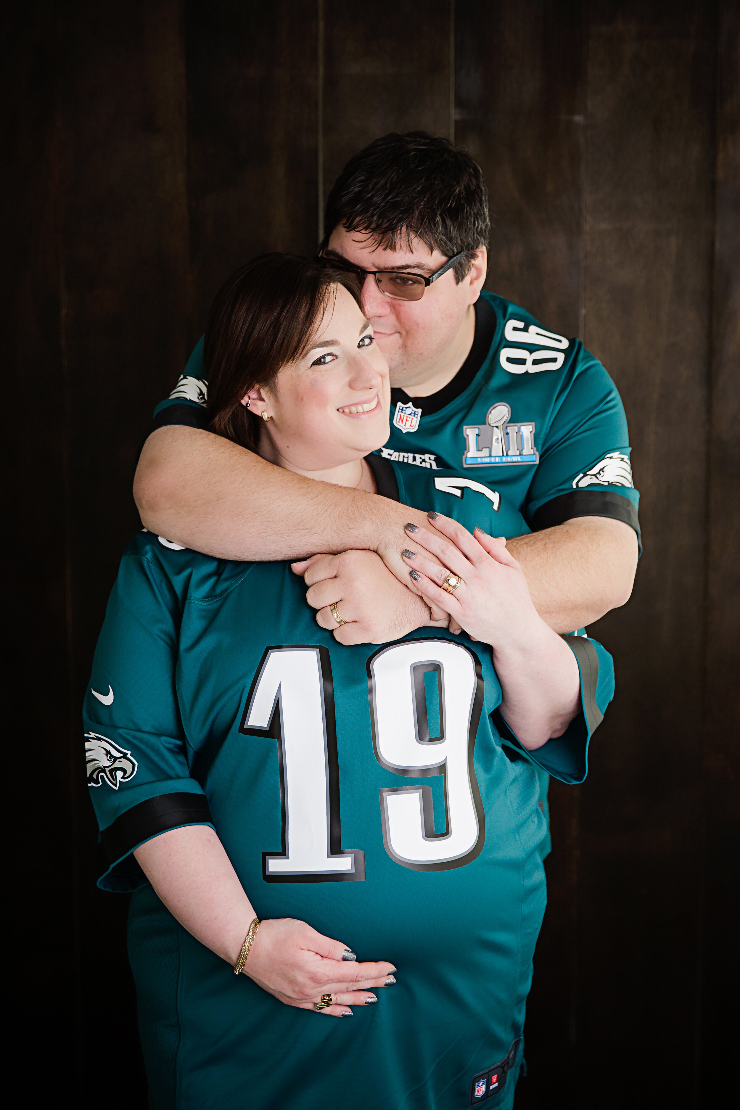 couple-wearing-eagles-jerseys-smiling-during-maternity-session