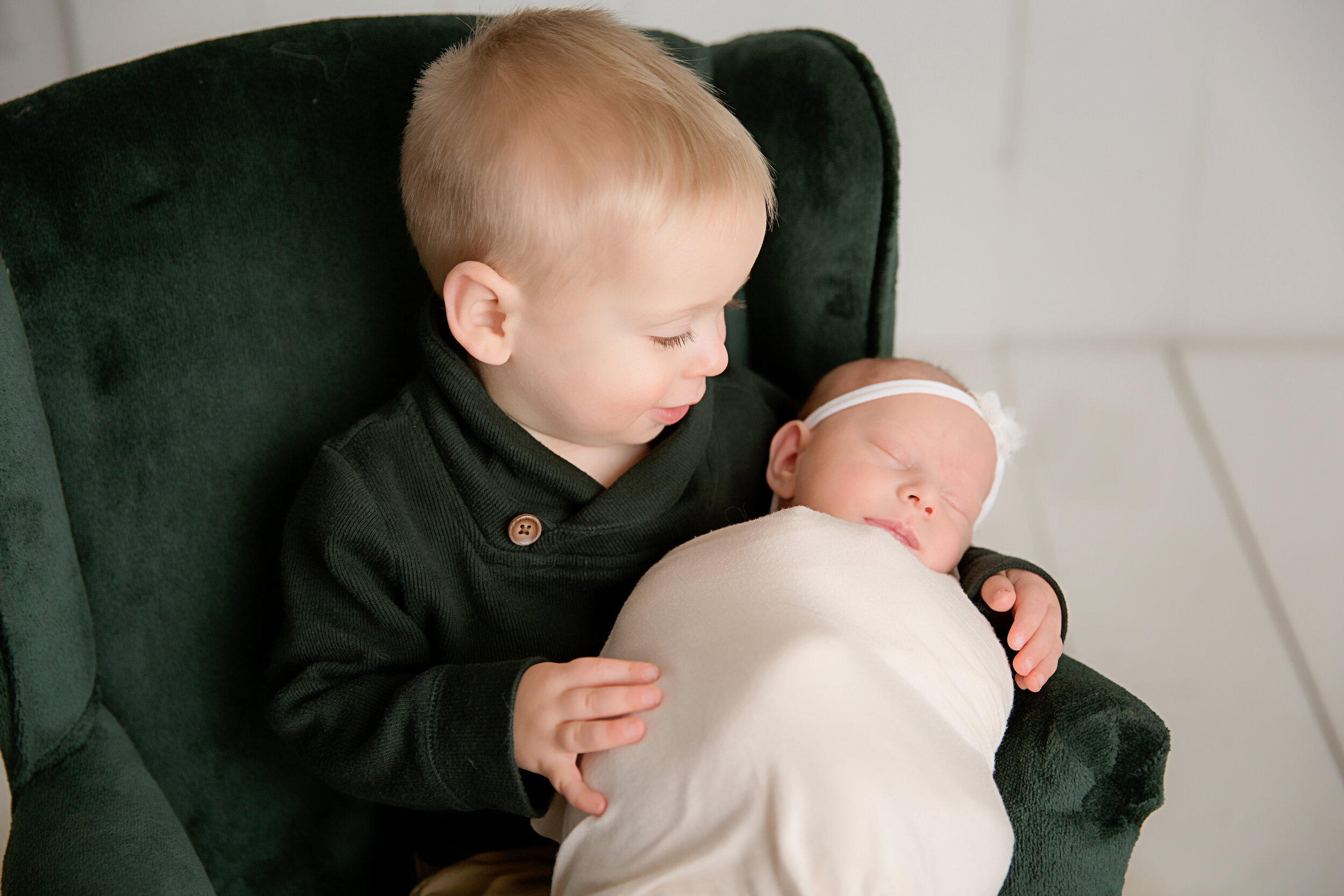 big-brother-holding-baby-girl-in-green-chair