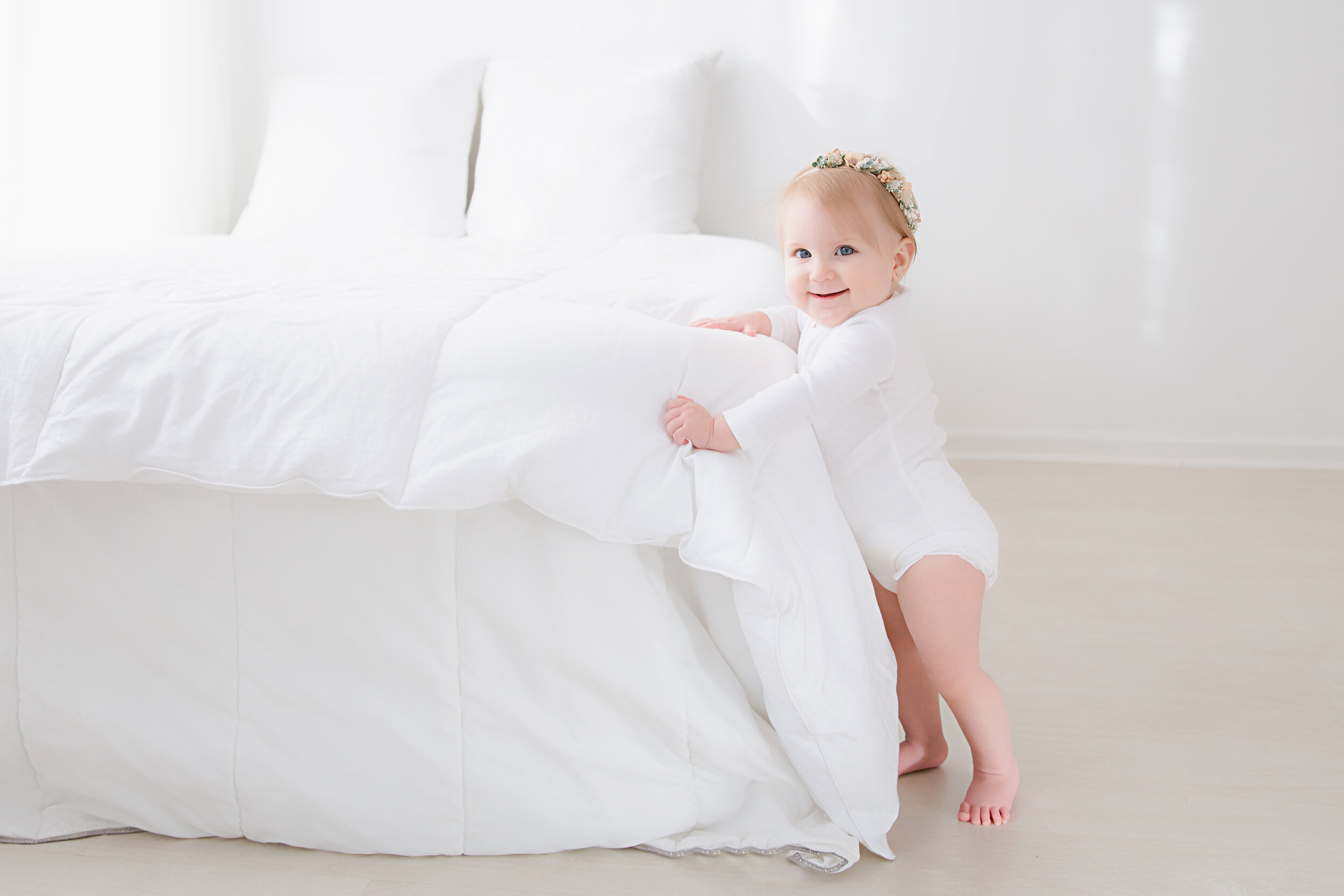 standing little girl next to a white bed