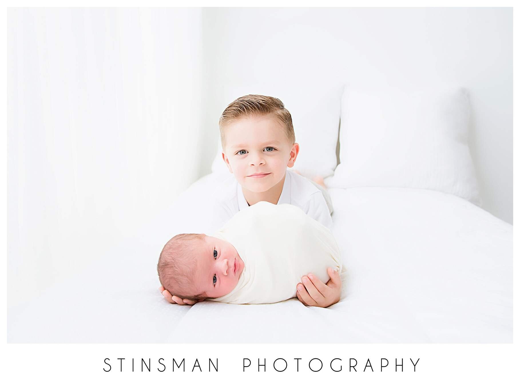 big-brother-holding-little-brother-for-newborn-session.jpeg