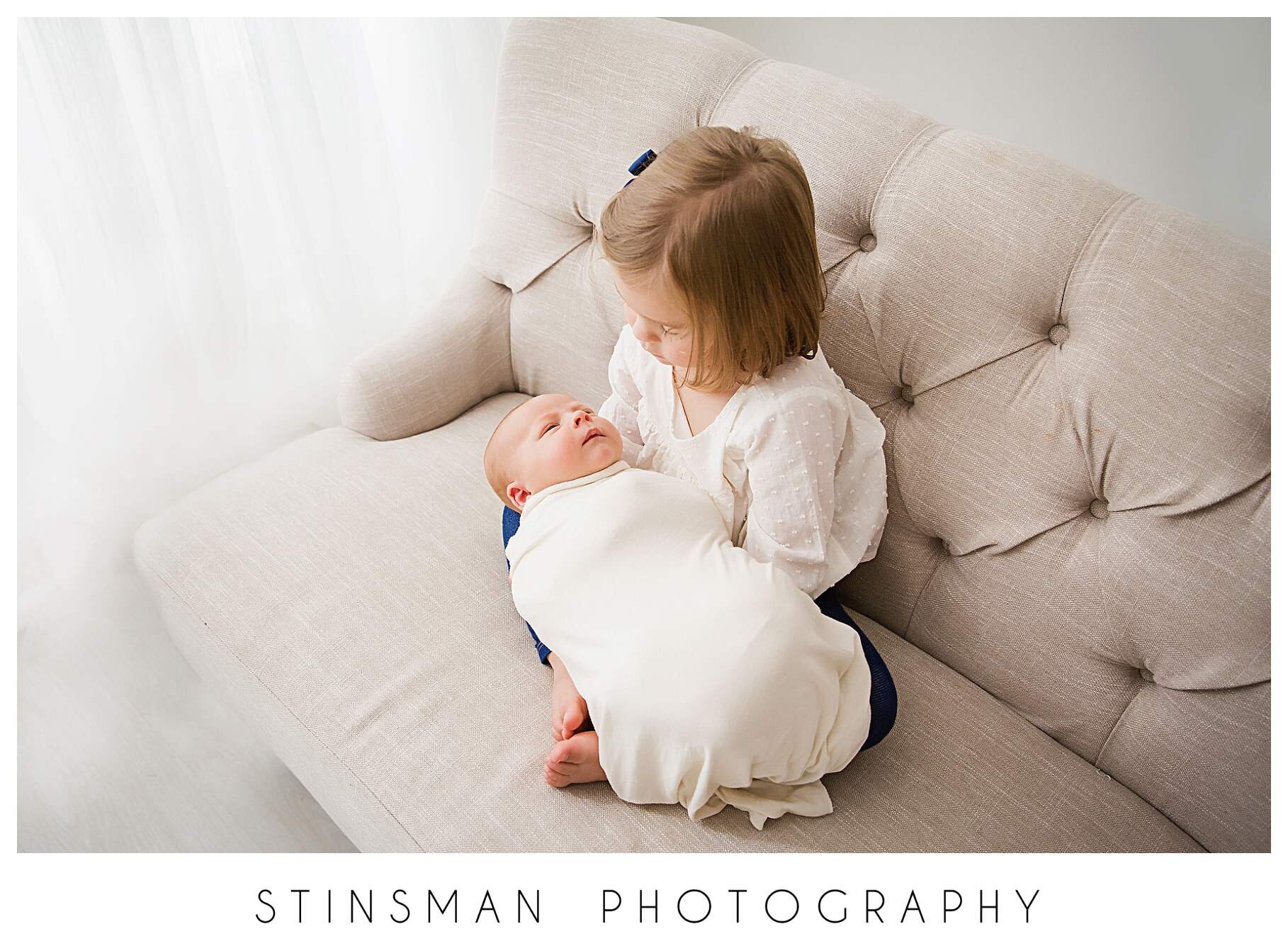 big-sister-holding-her-newborn-baby-brother-for-newborn-photos.jpeg